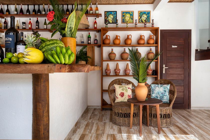 Interior rústico de um café com exposição de frutas, prateleiras de cerâmica e uma pequena mesa com cadeiras.