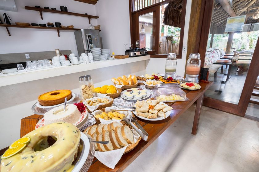 Interior rústico de um café com exposição de frutas, prateleiras de cerâmica e uma pequena mesa com cadeiras.