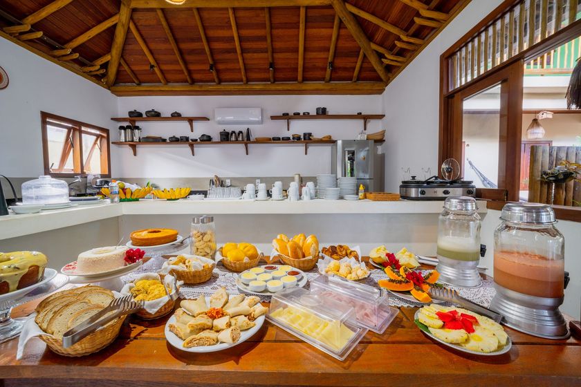 Exposição de frutas tropicais e garrafas de bebidas alcoólicas em uma prateleira de madeira em um restaurante bem iluminado.