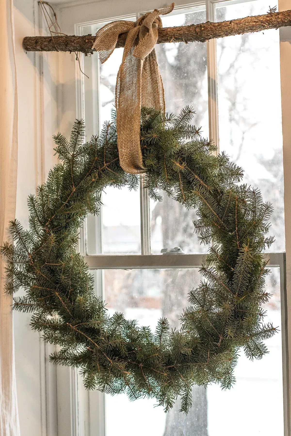 A christmas wreath is hanging on a window sill. A christmas wreath is hanging on a window sill.