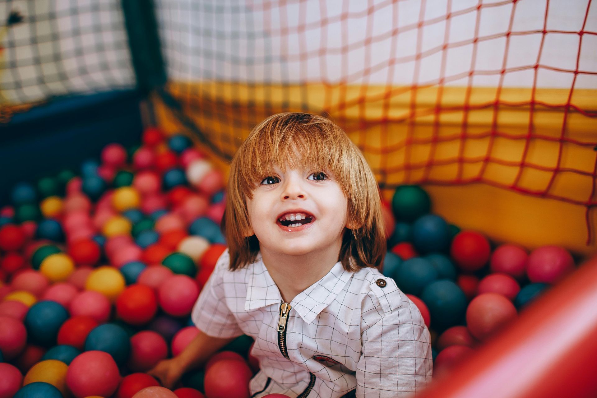 A young boy is sitting in a ball pit filled with colorful balls.