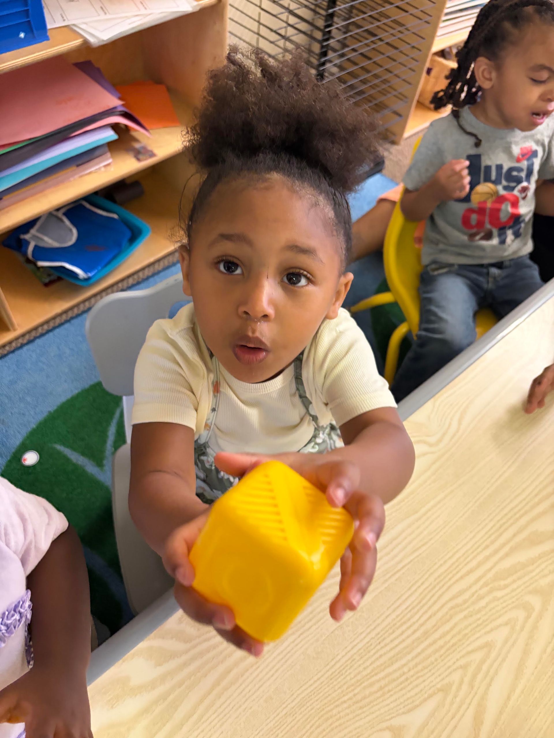 A little girl is dressed as a fireman in a classroom.