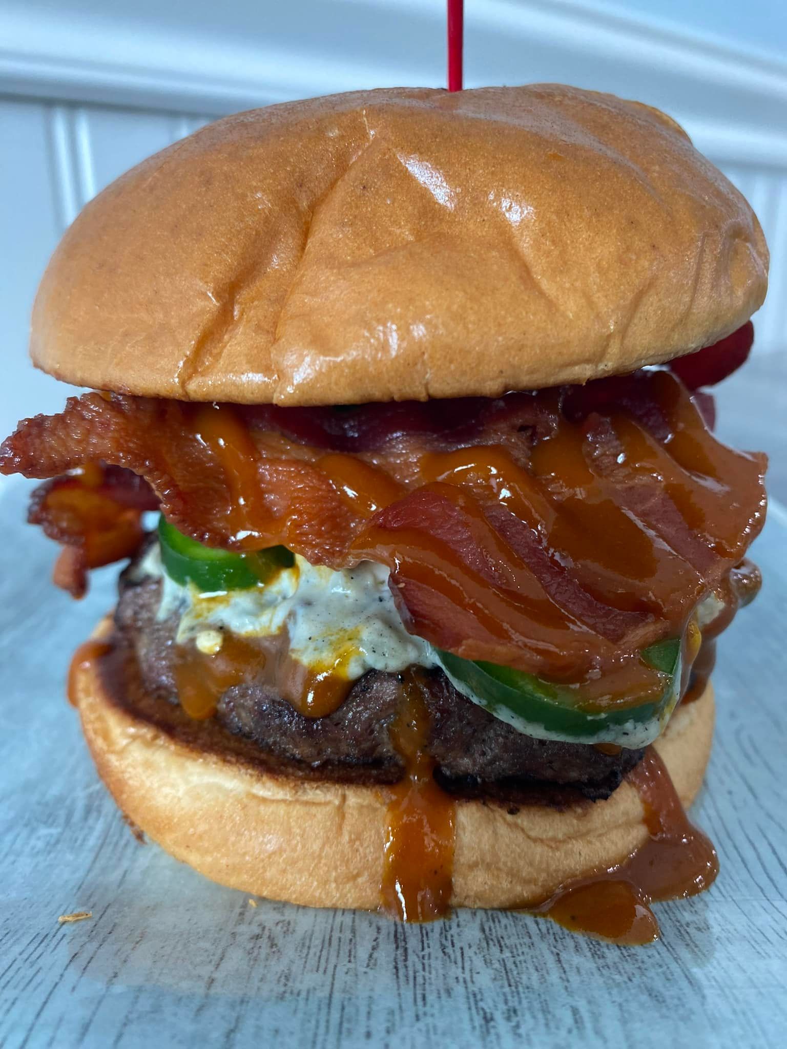 Bacon cheeseburger on a bun with lettuce, tomato, and sauce, with cheese melting over the patty.