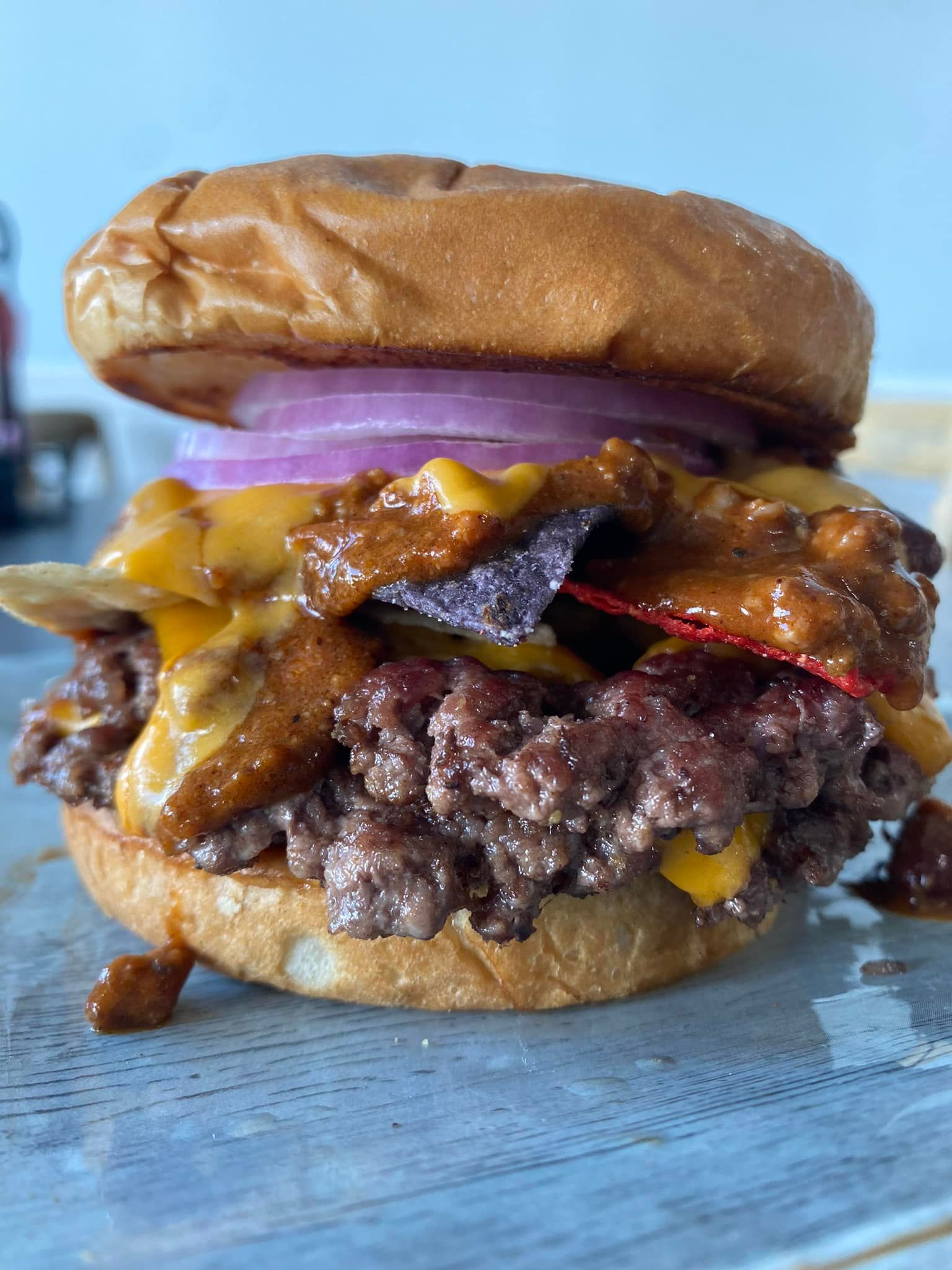 Close-up of a cheeseburger with melted cheese, red onion, and bacon on a bun