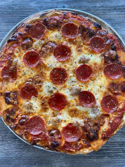 Pepperoni pizza on a round metal tray, with a browned cheesy crust.