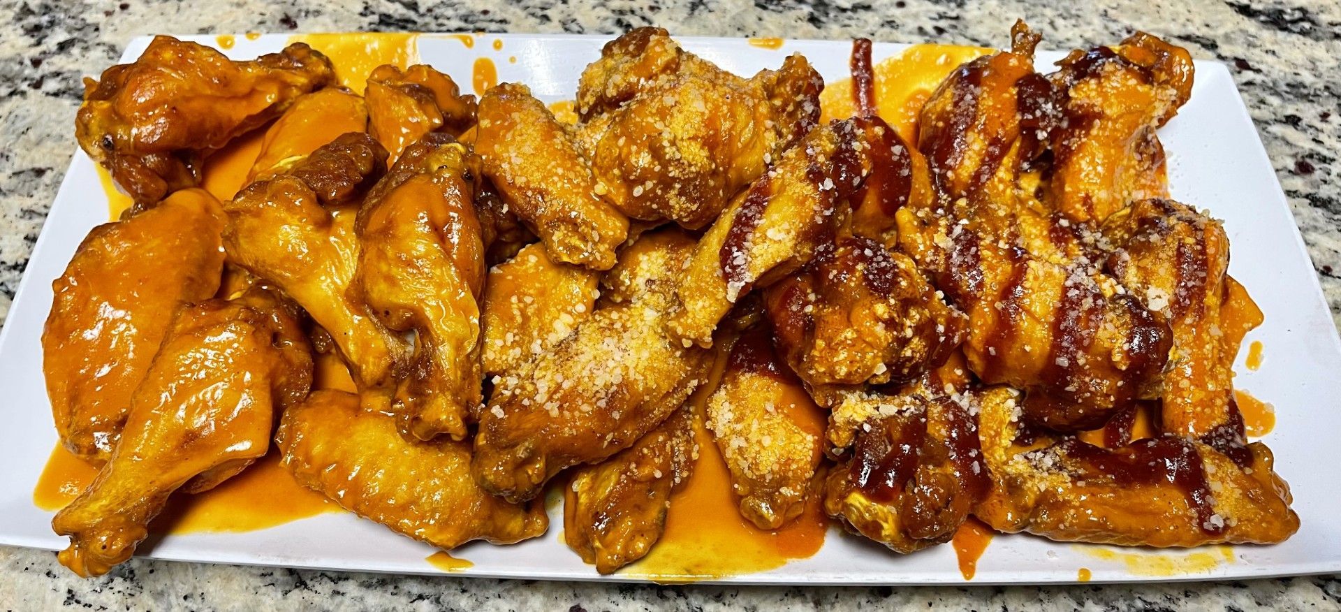 Tray of glazed chicken wings and pieces on a white platter with dark caramelized sauce