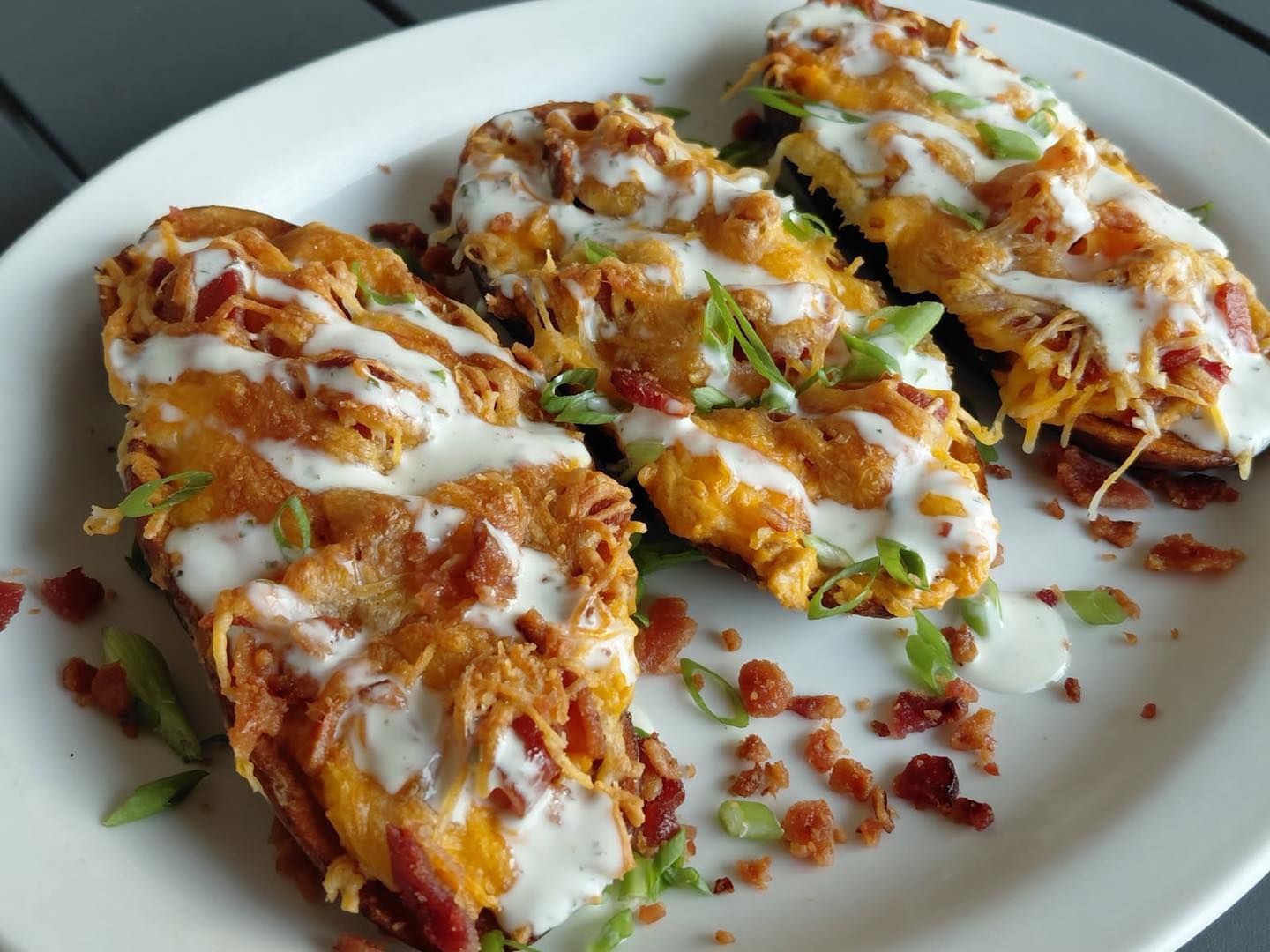 Plate of cheesy enchiladas topped with sauce and green garnish on a white dish