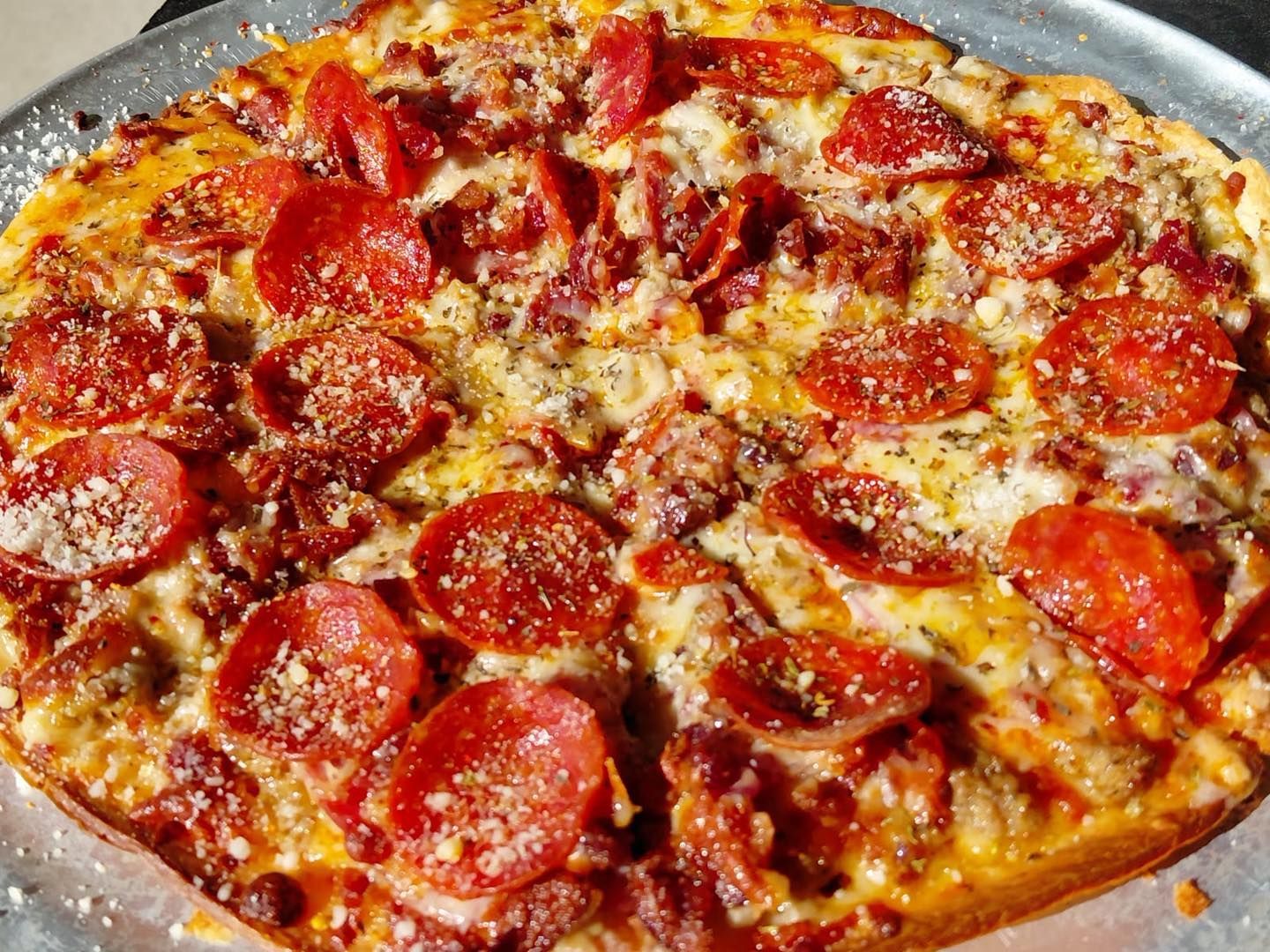 Pepperoni pizza with melted cheese on a round metal tray