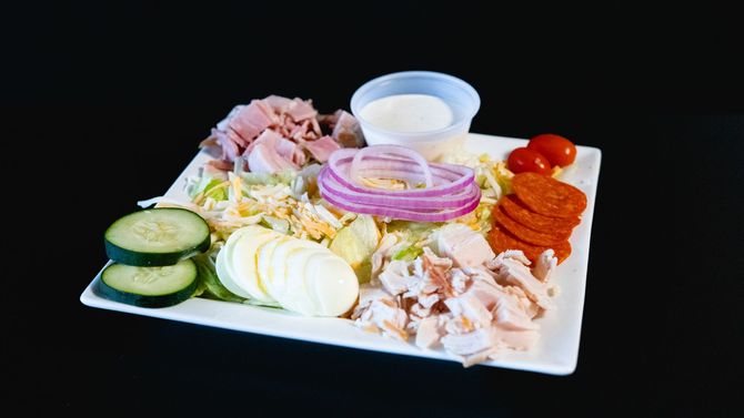 Assorted sliced vegetables, meats, and dips arranged on a white serving platter.