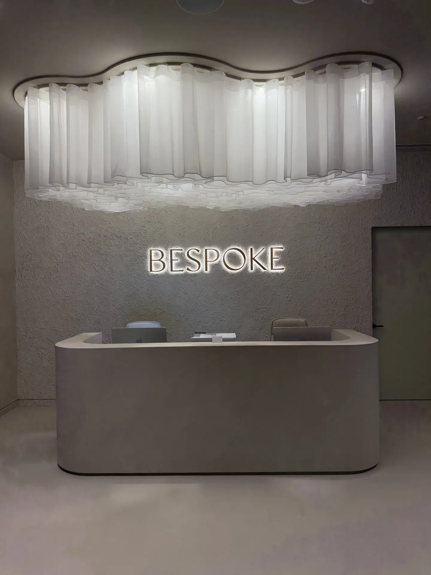 Reception desk in a Bespoke shop with neon sign. A cloud-shaped light hangs above the desk.