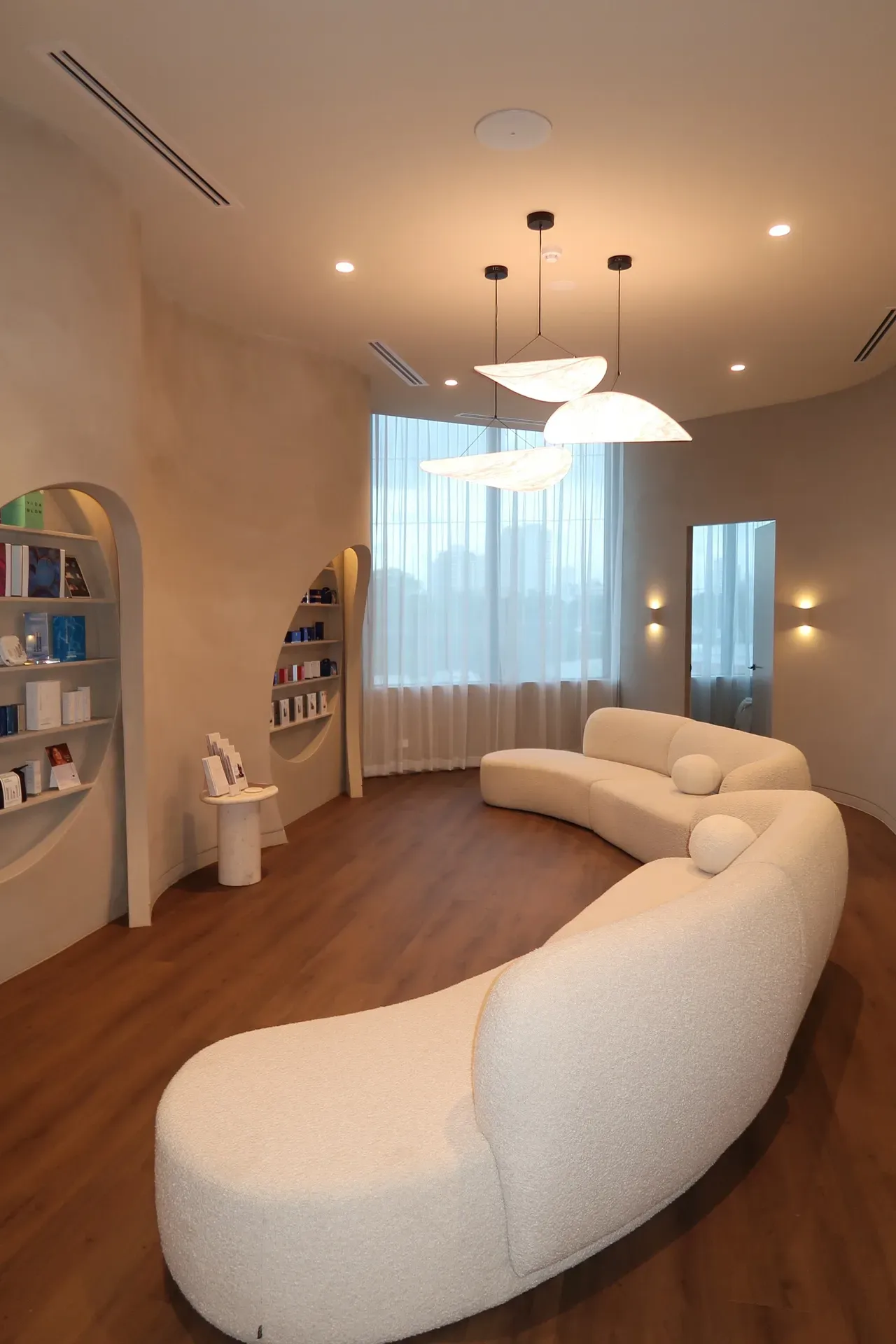 Curved waiting room with a white sofa, built-in shelves, and a large window.