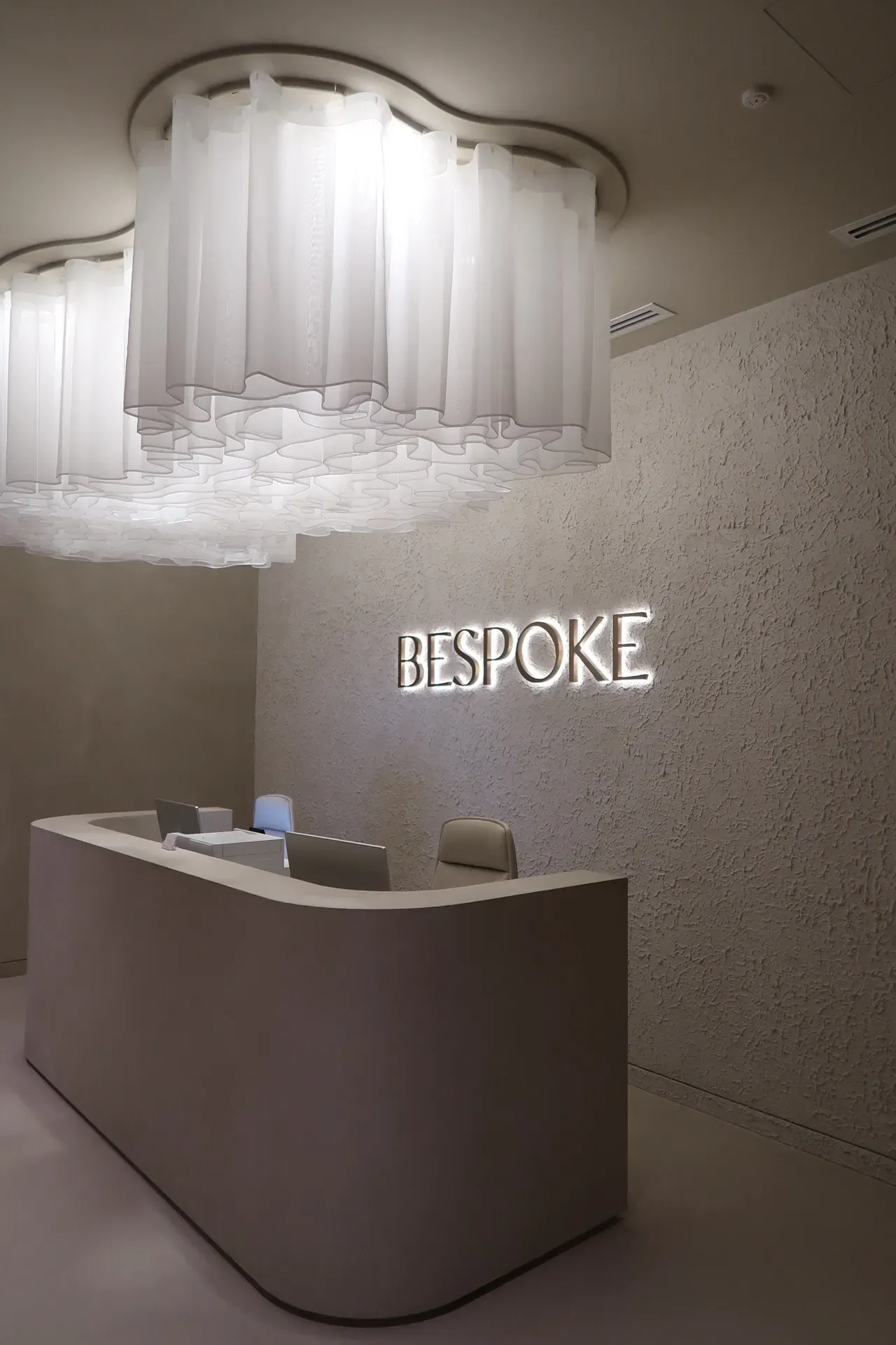 Reception area with a light-colored desk and textured wall,