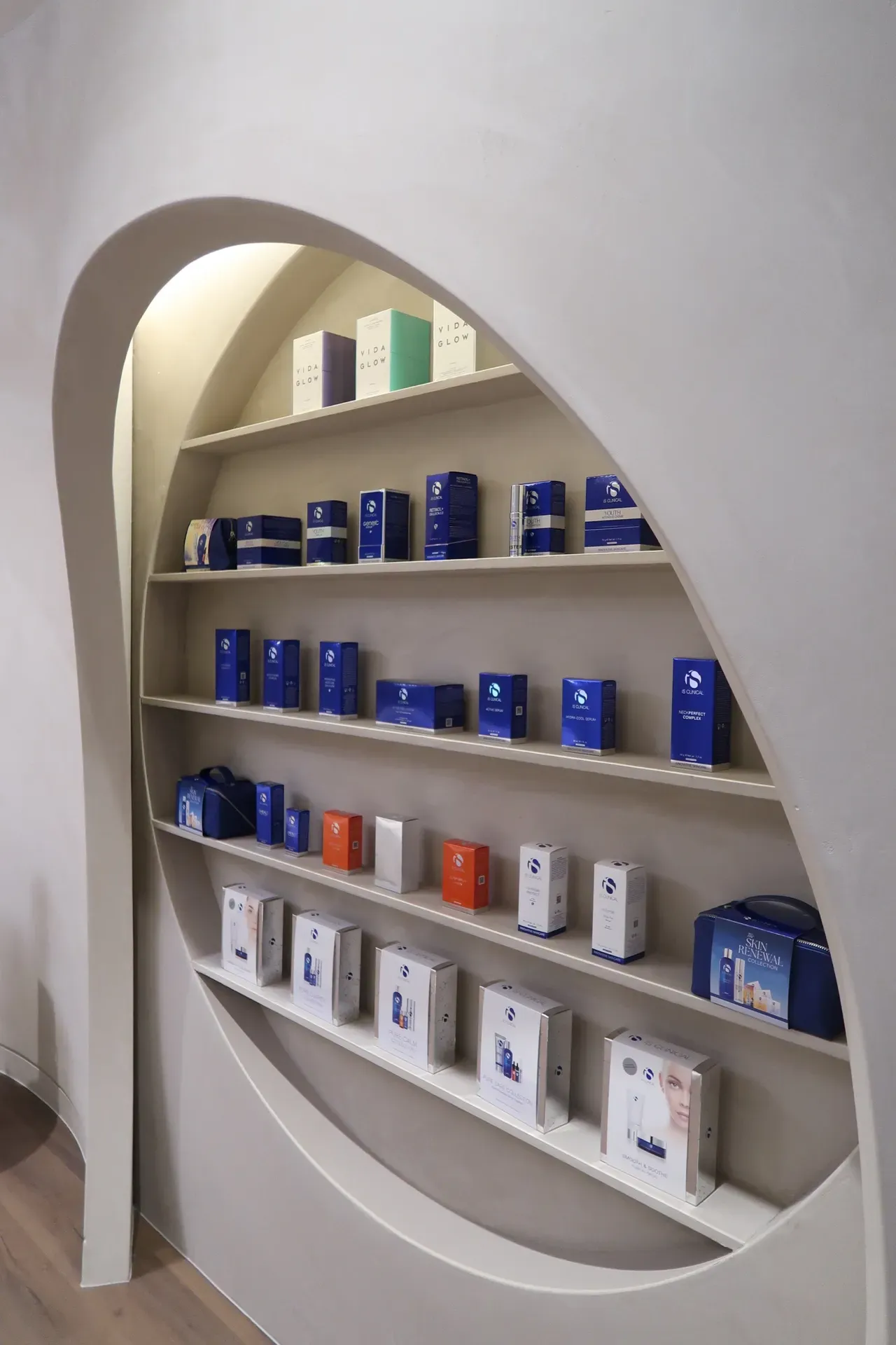Shelves displaying beauty products inside a store, with arched frame, featuring various blue and white boxes.
