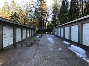 A row of white garage doors are lined up in a parking lot.