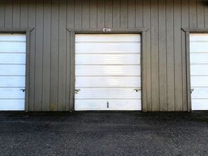 There are three garage doors on the side of a building.