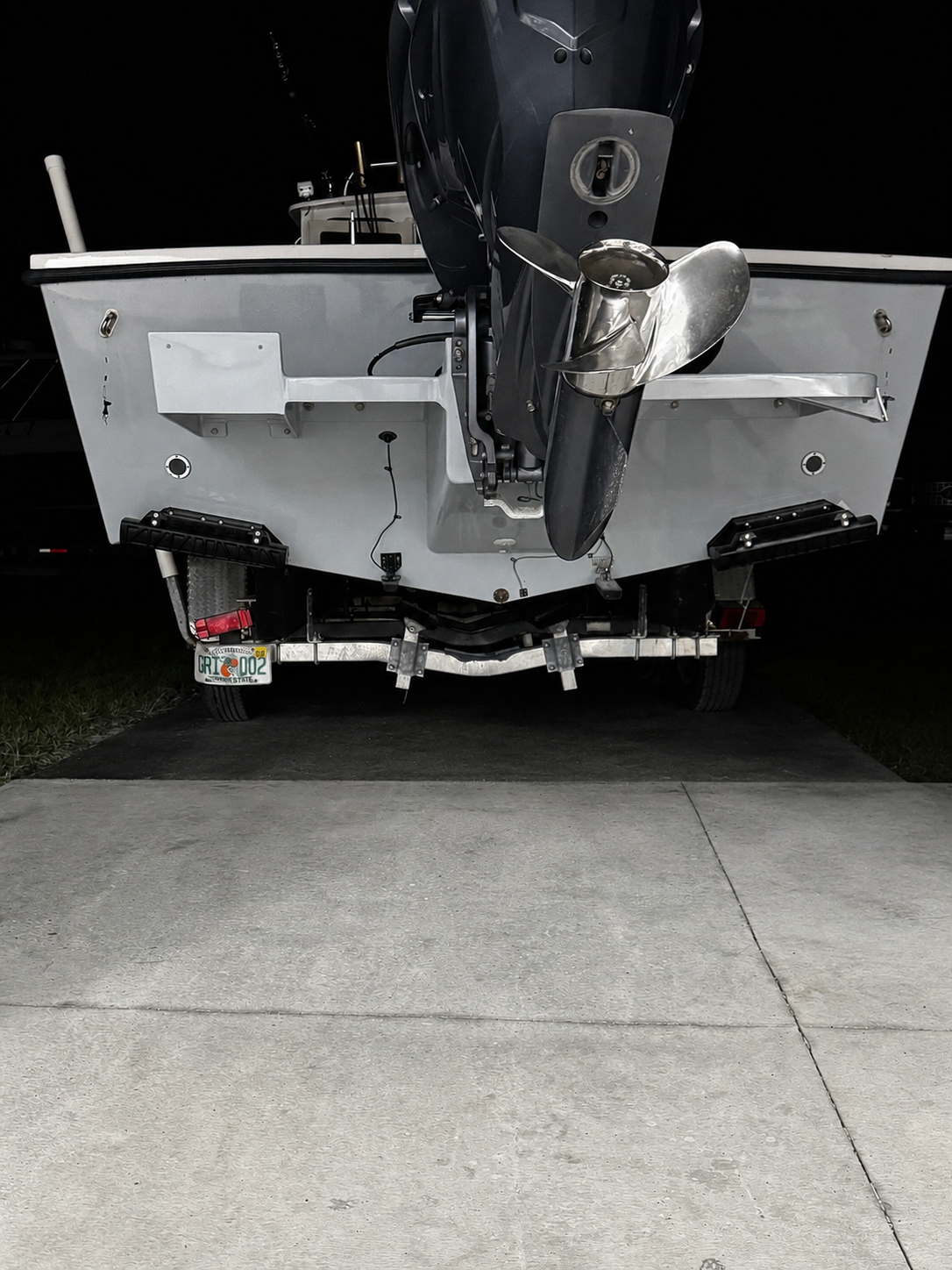 Front view of a boat’s stern and outboard motor on a trailer in a dim garage