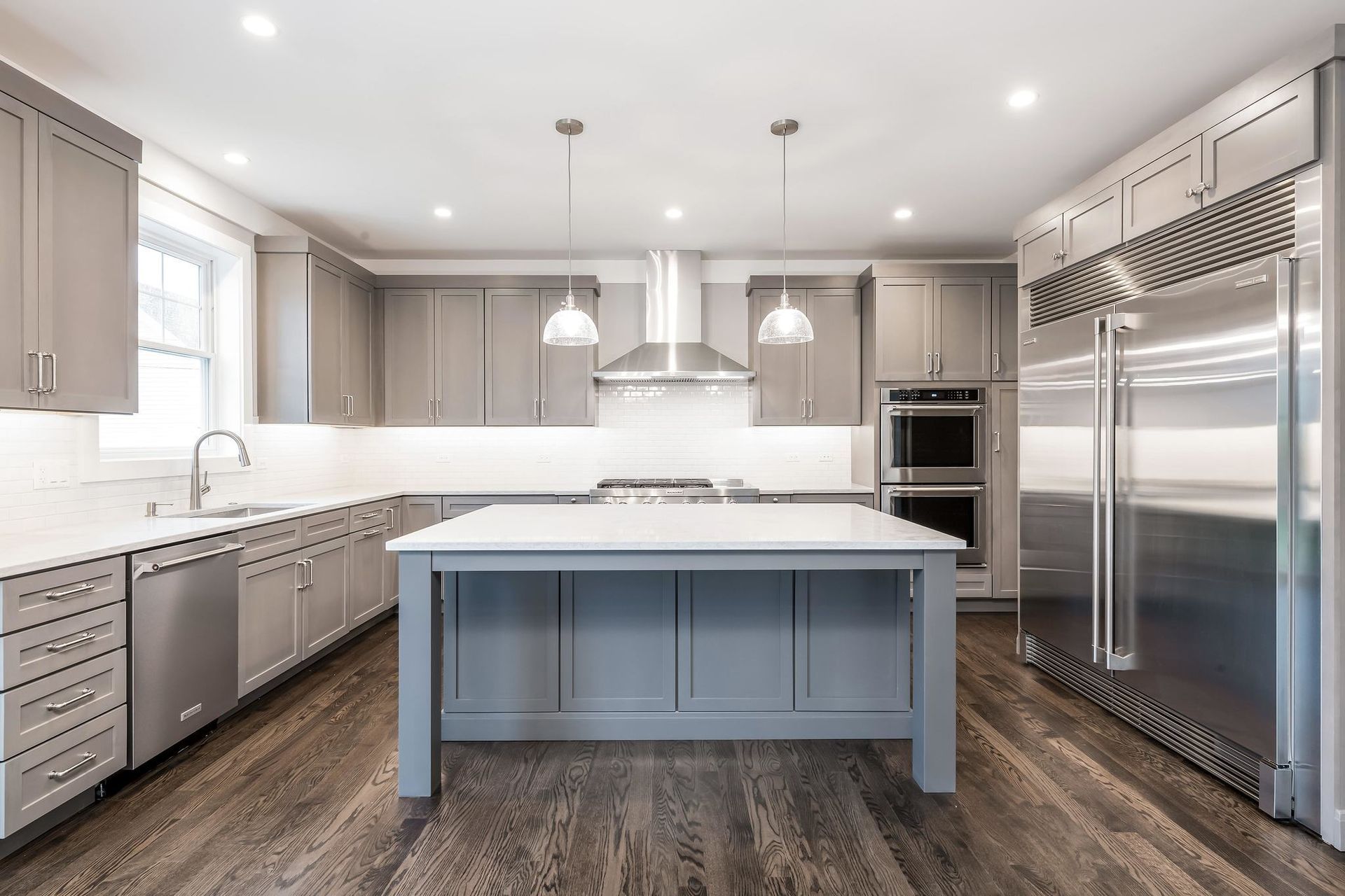 Gray kitchen with island, stainless steel appliances, and hardwood floors.