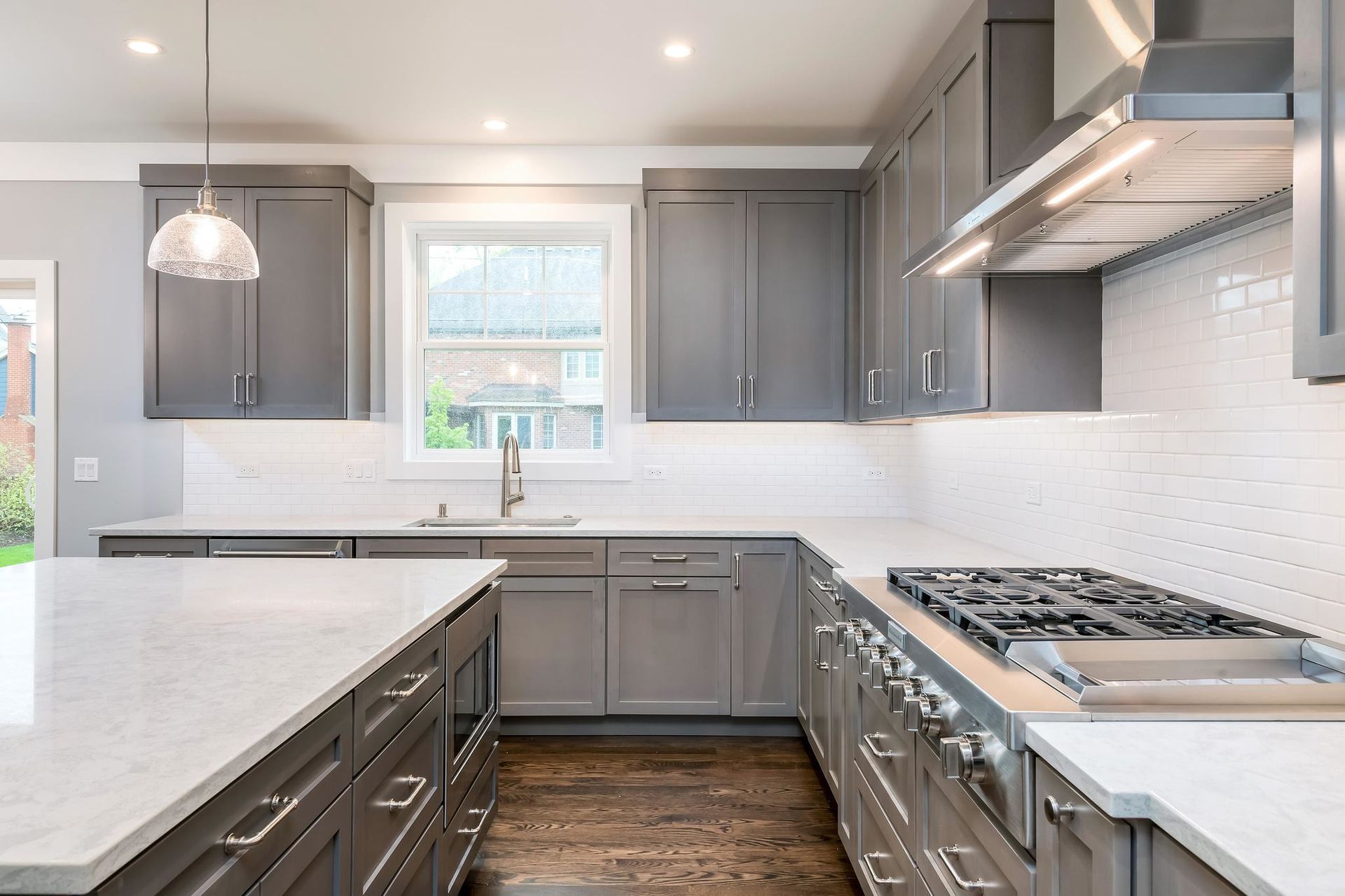 Gray kitchen with white countertops, stainless steel appliances, and a window.