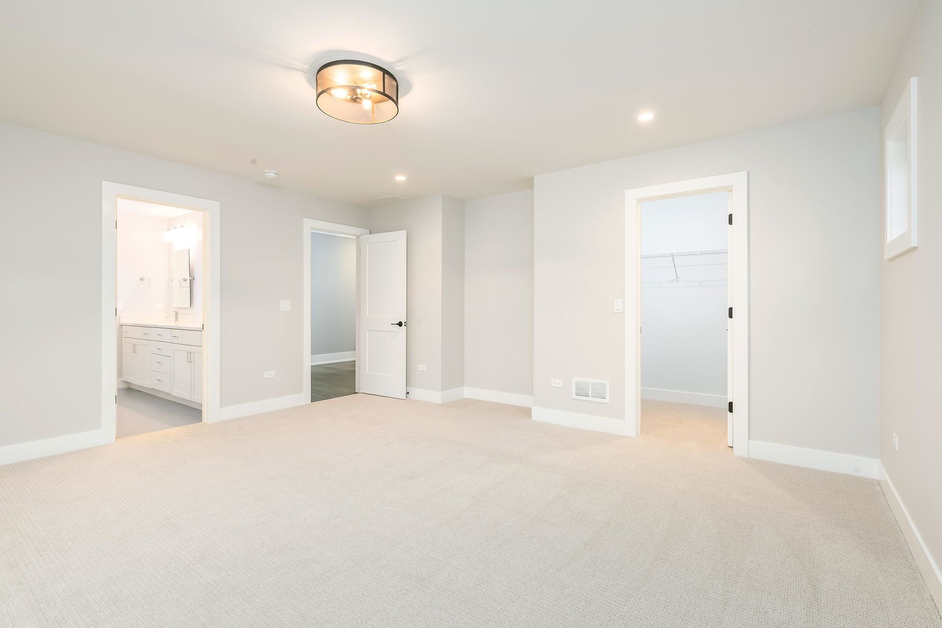 Empty bedroom with gray walls, white doors, light carpet, and a flush mount ceiling light.
