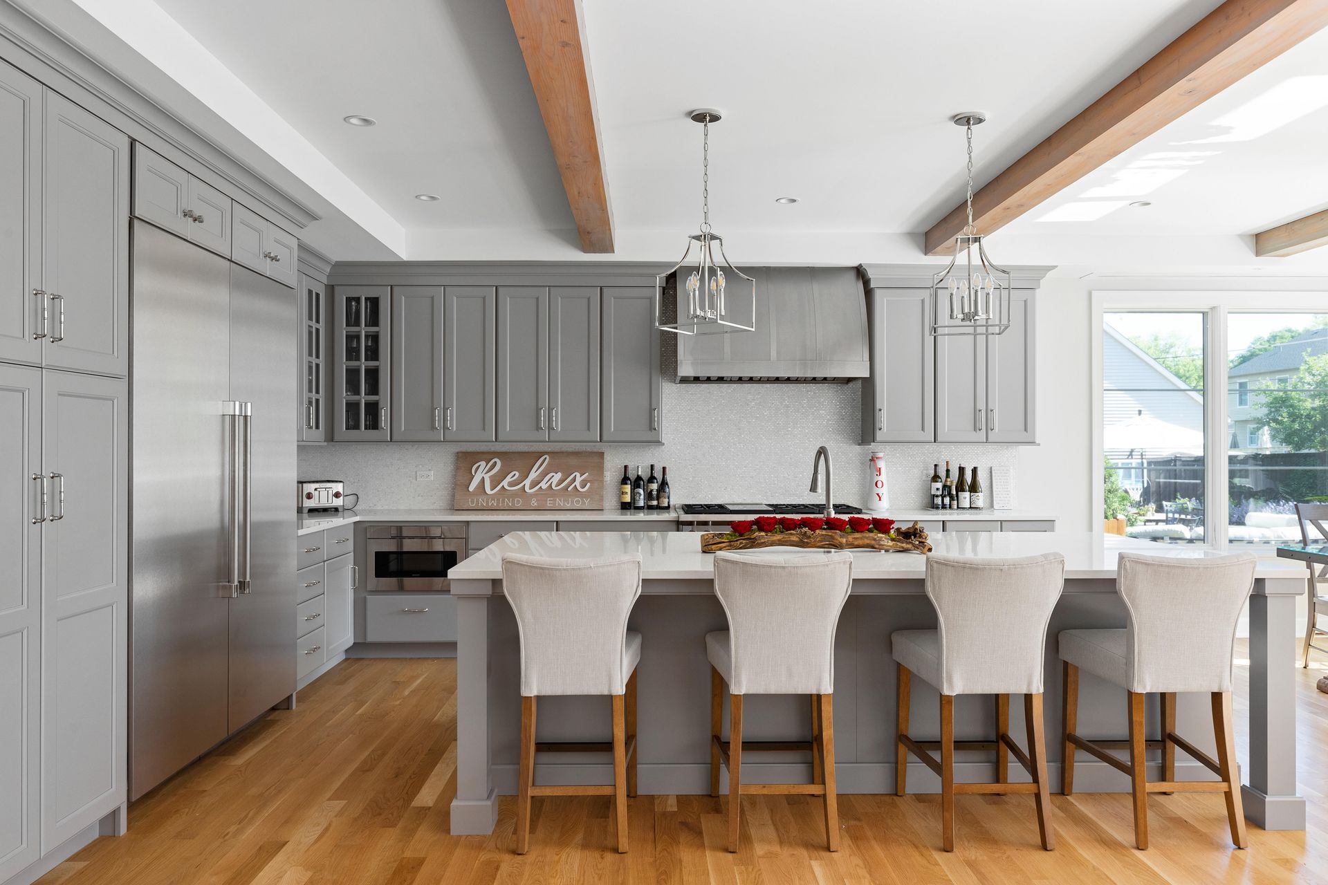 Gray kitchen with island, stools, and stainless steel appliances.