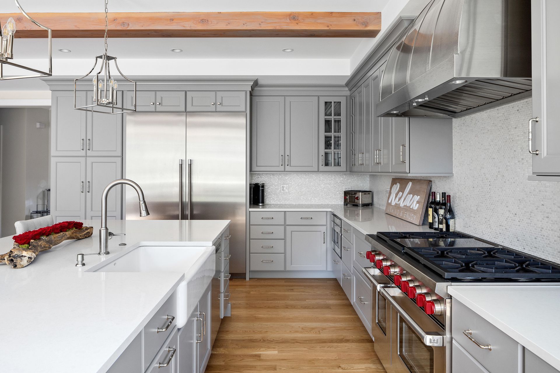 Modern gray kitchen with stainless steel appliances, white countertops, and wood floors.
