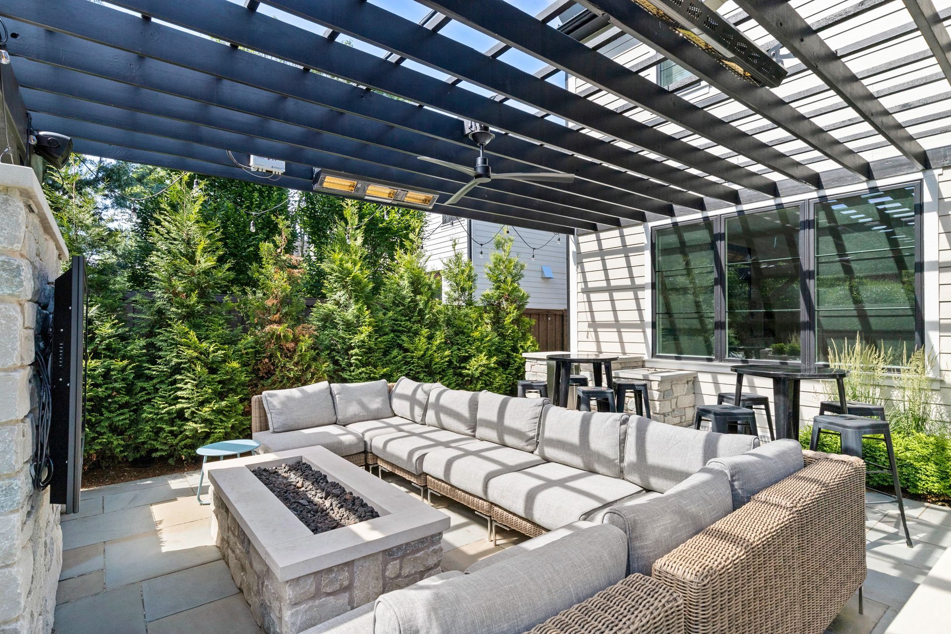 Outdoor patio with sectional seating, fire pit, and overhead pergola.