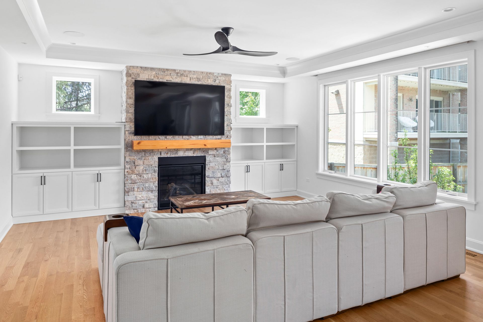 Living room with a large white sectional sofa, fireplace, and built-in white bookshelves.