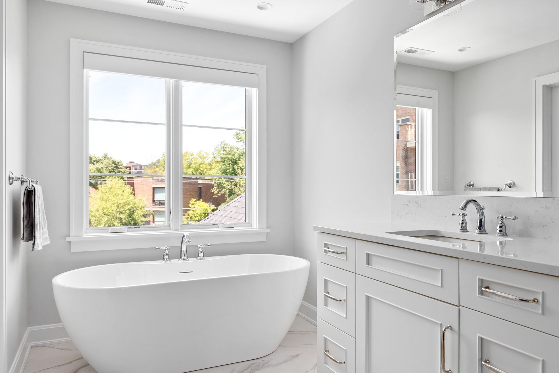 White bathroom with a soaking tub, vanity, and window.