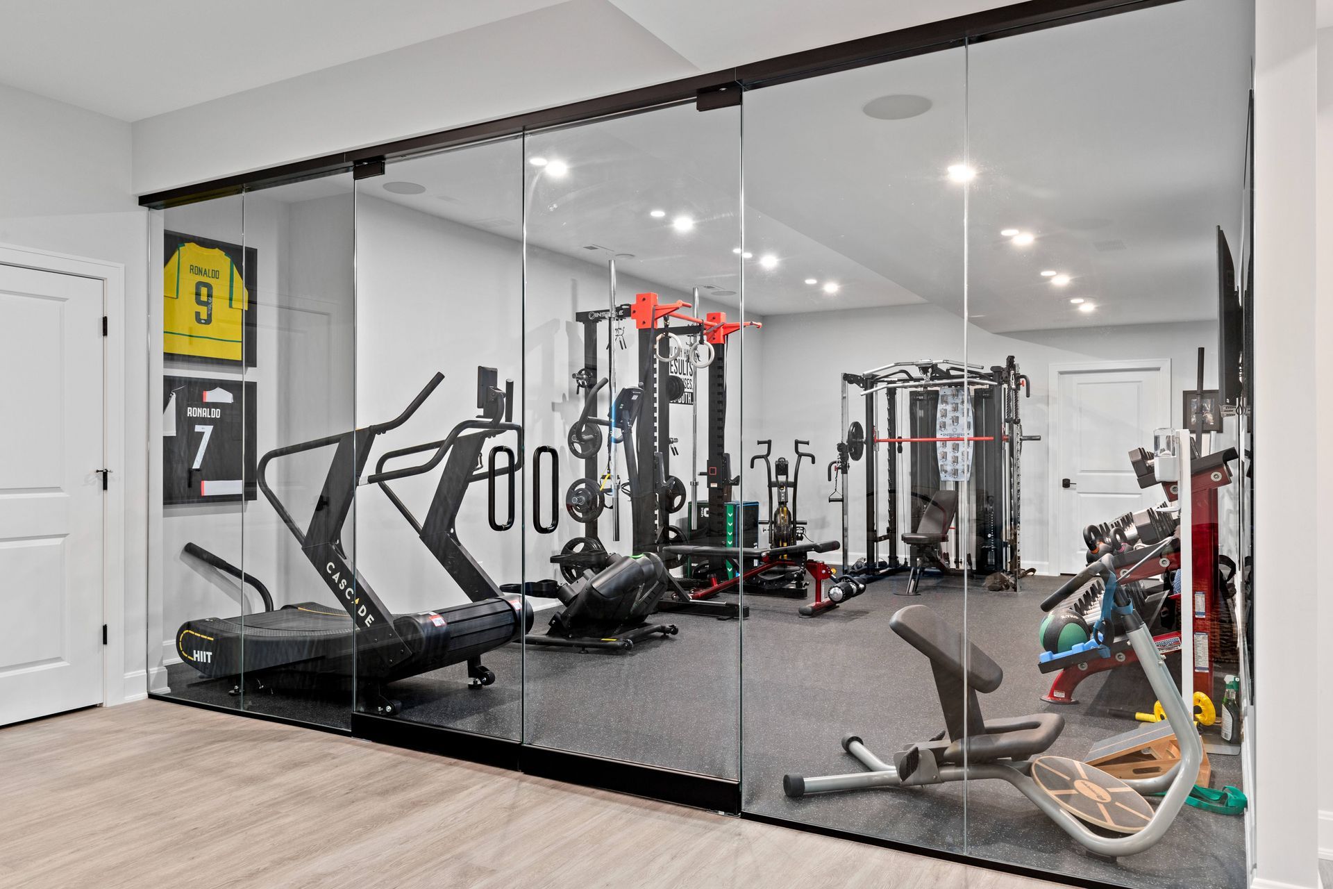 Home gym with glass sliding doors, containing exercise equipment on black flooring.