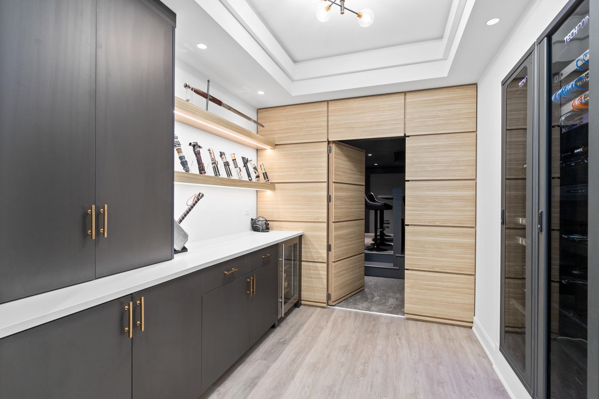 Modern home bar with gray cabinets, wine storage, and a doorway to a gym.