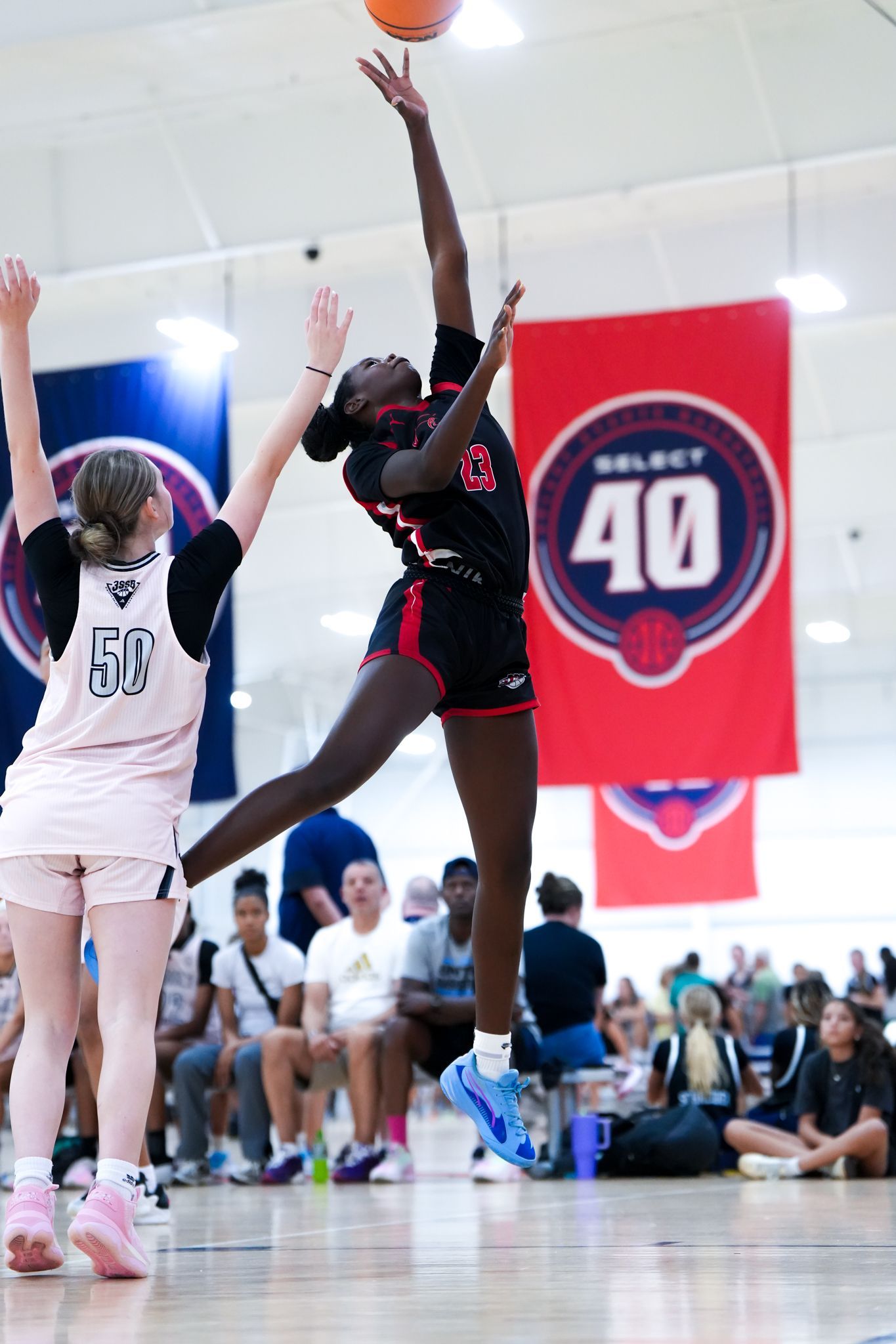 Basketball player in black uniform shoots over a defender during a game, with a