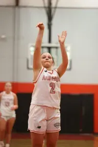 Basketball player in white and red uniform shooting a free throw, in a gymnasium.