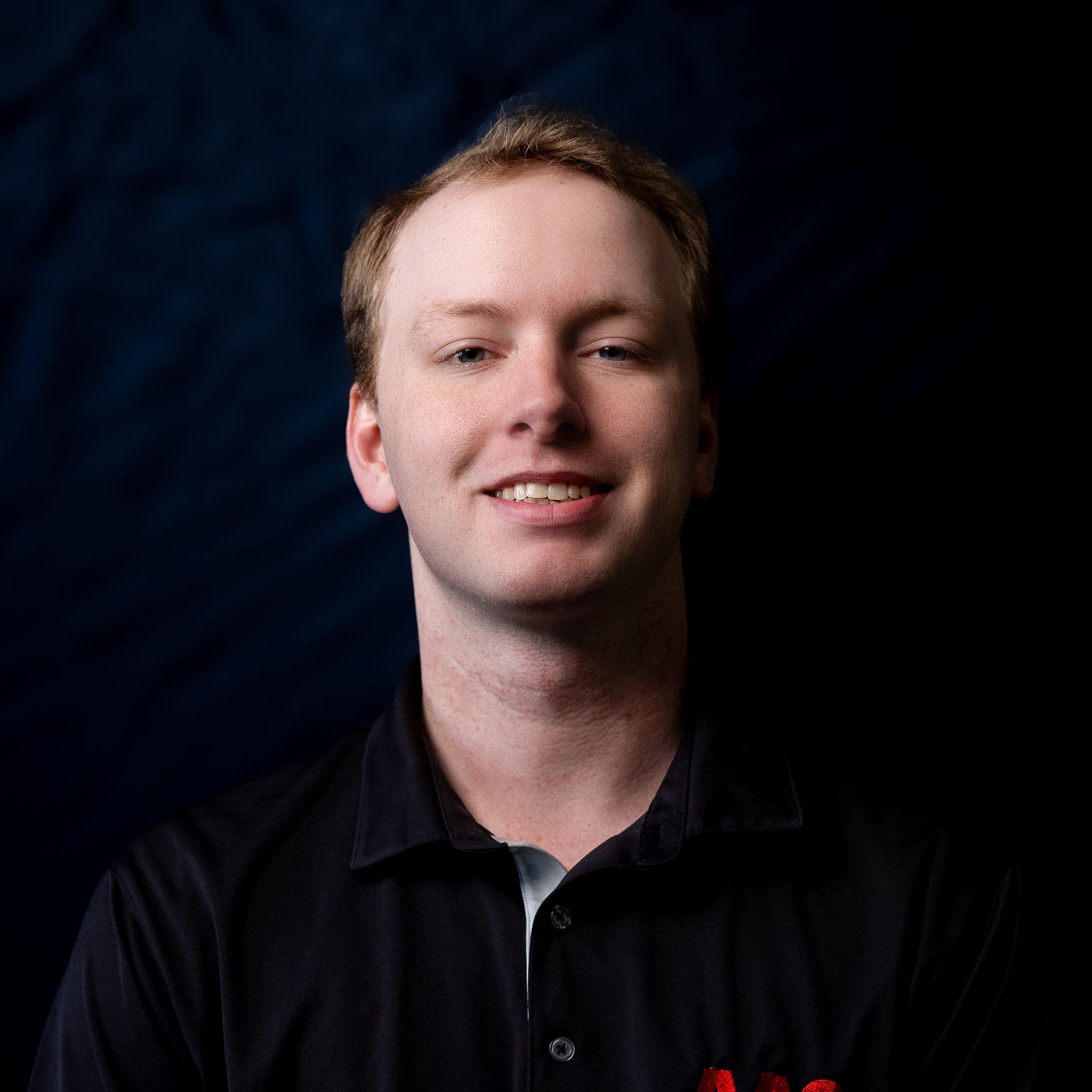 Smiling man in a black shirt against a dark background