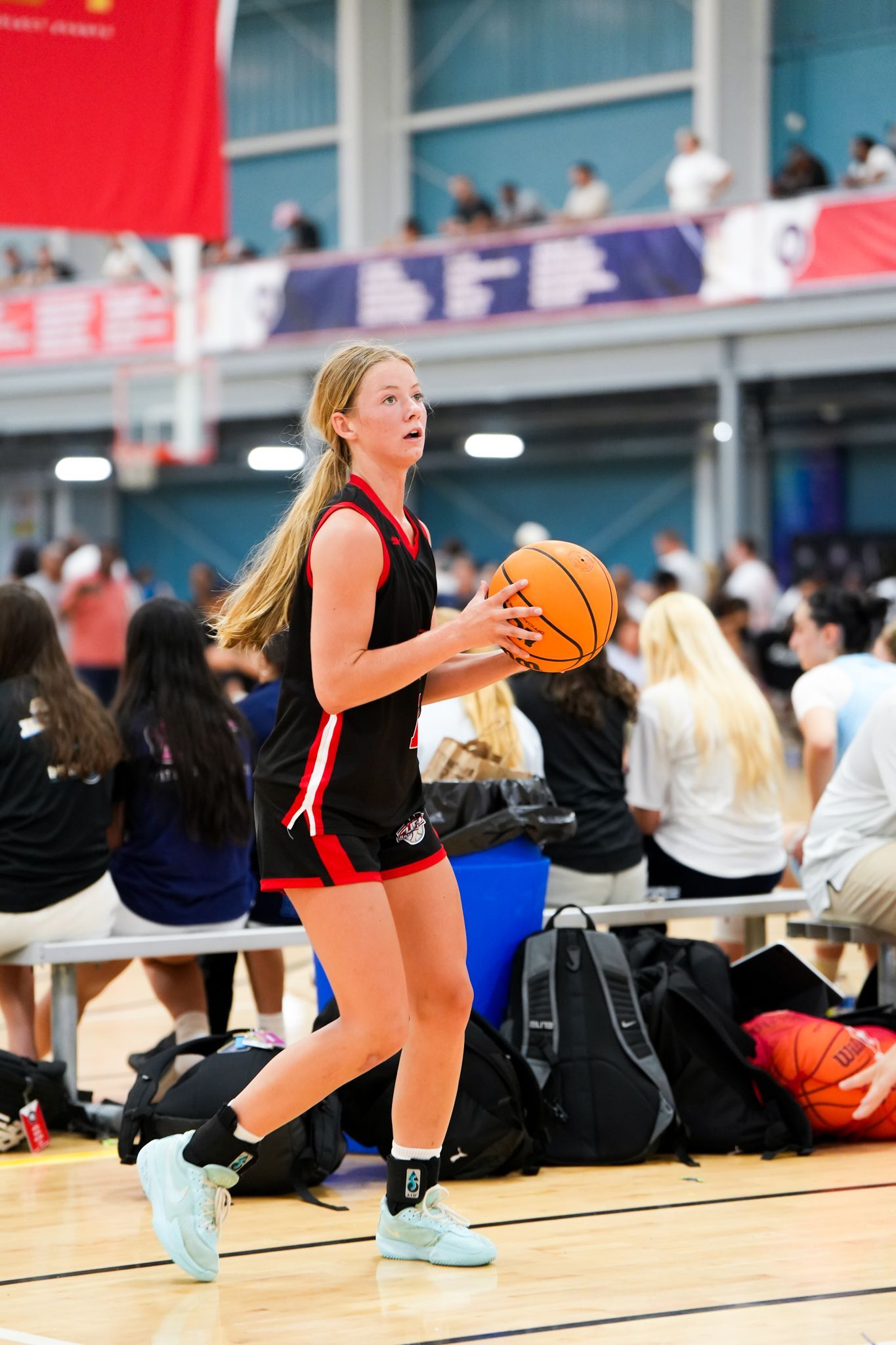 Girl in black basketball uniform holding ball on court, preparing to shoot.