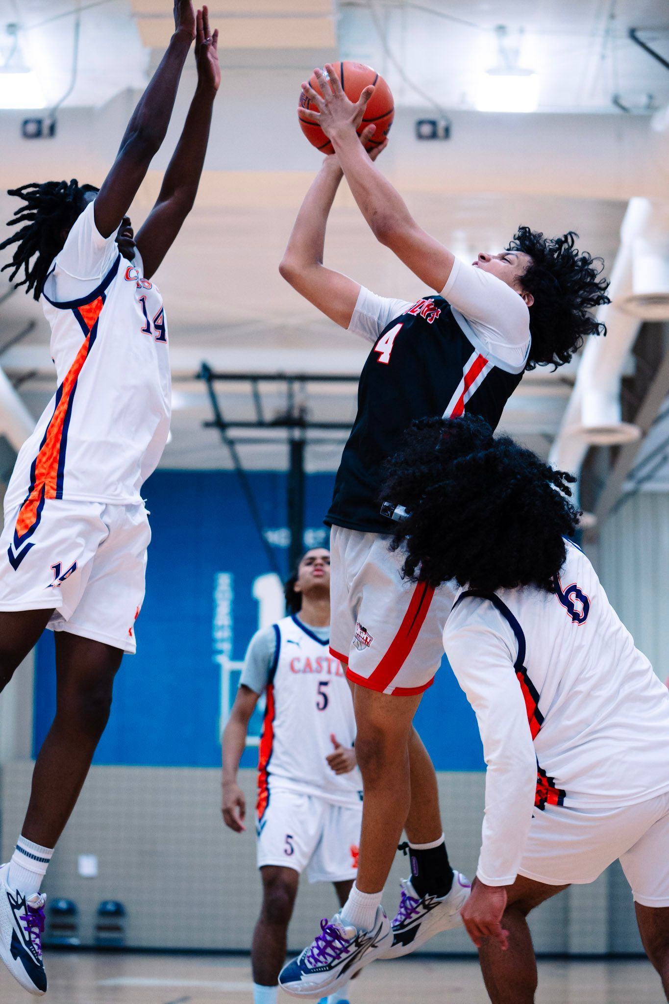 Basketball players jumping to reach for the ball during a game.