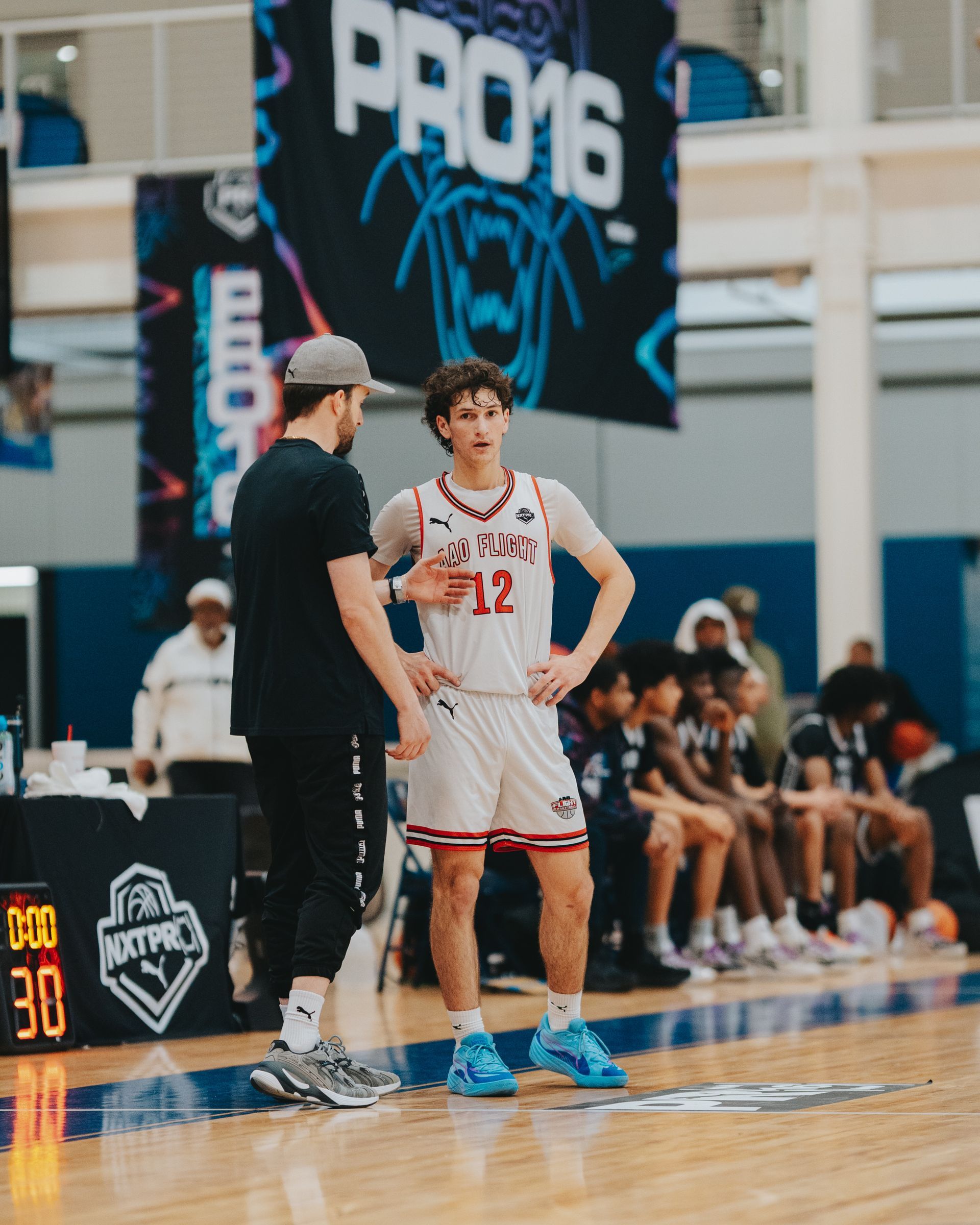 Basketball player in red jersey with coach on court during a game.
