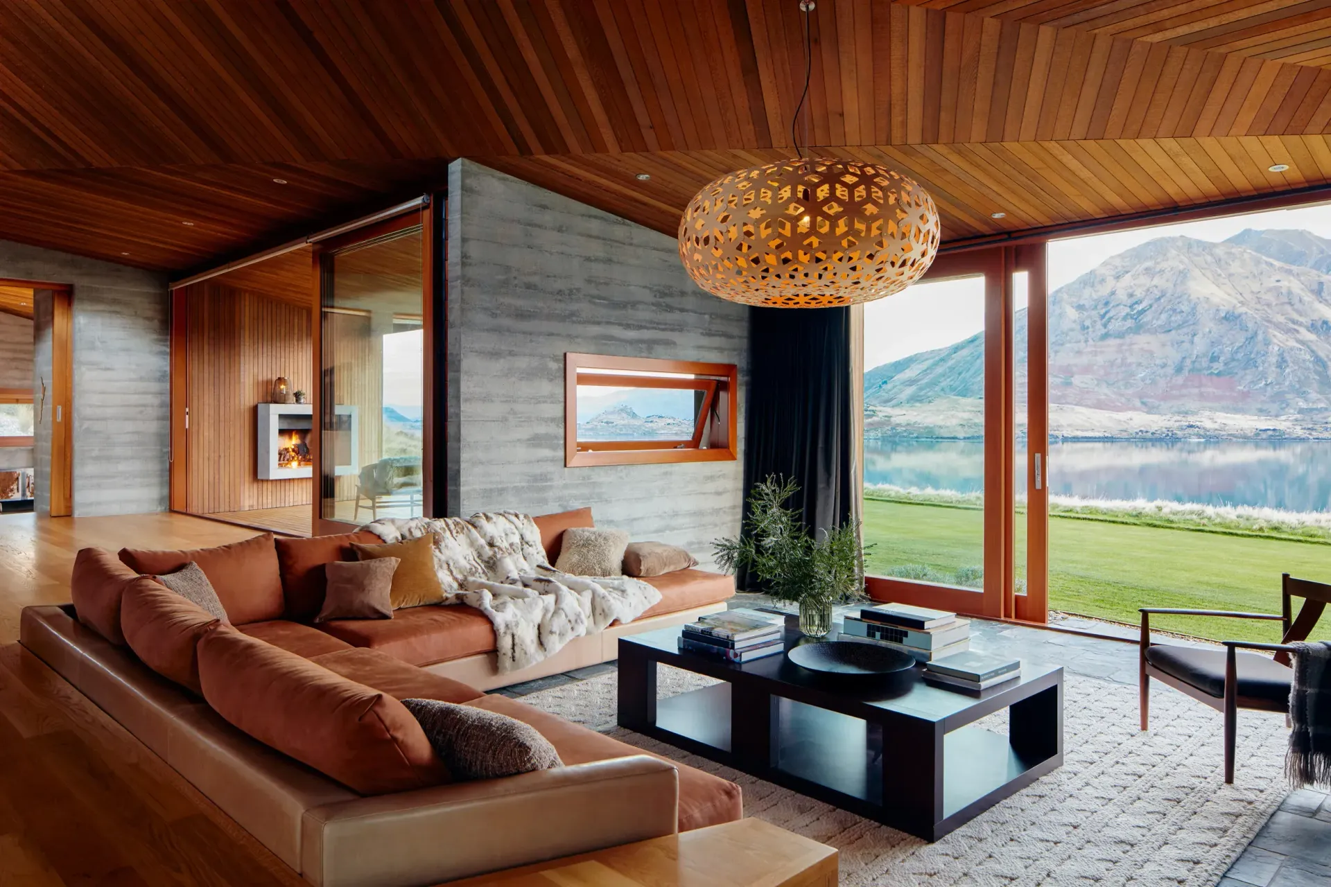 A living room with a couch and a coffee table with a view of a lake.