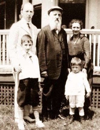 A black and white photo of a family standing in front of a house.