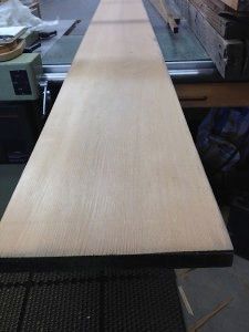 A long piece of wood is sitting on top of a table saw.