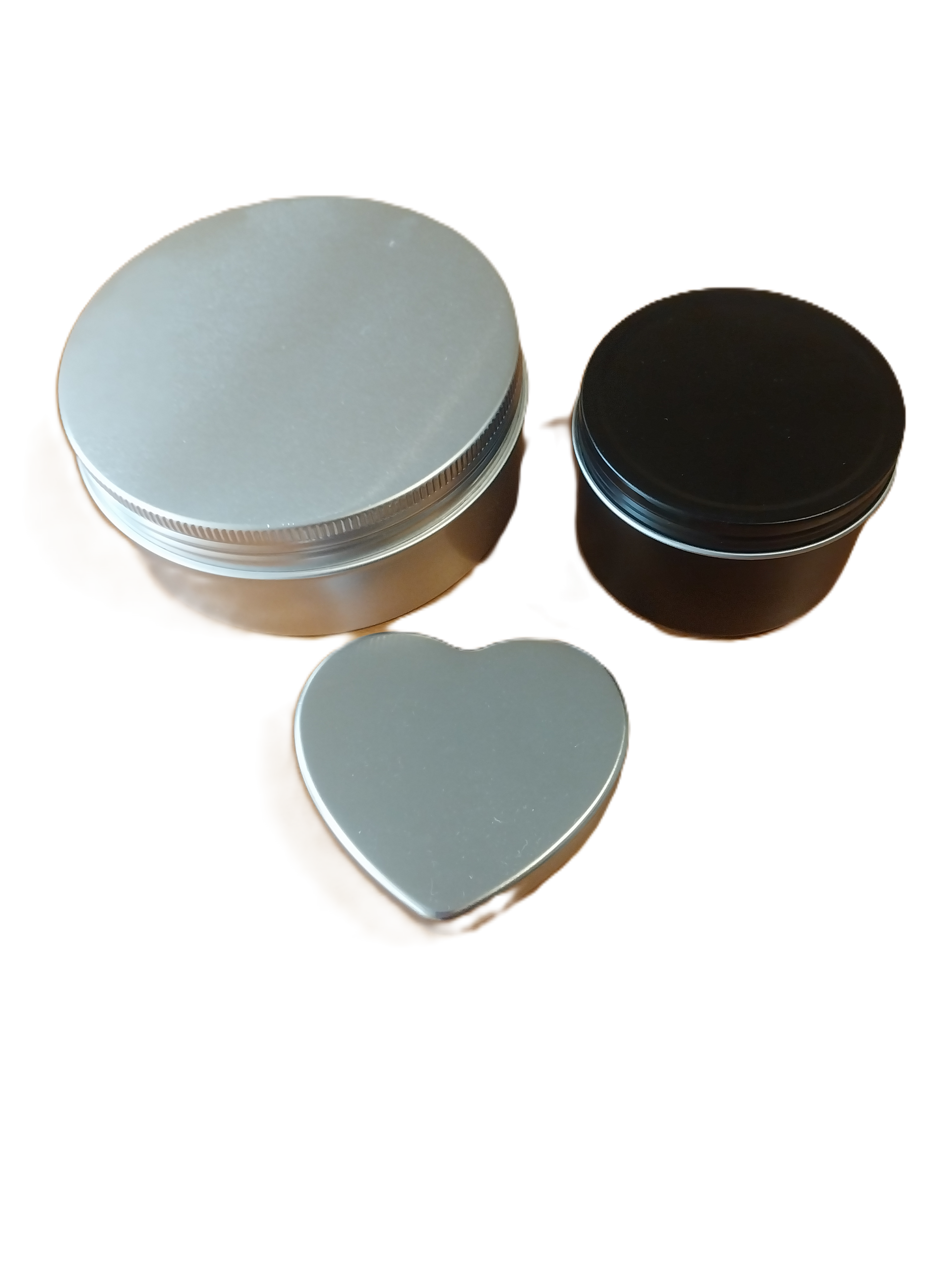 Three small tins - one round and silver, one cylindrical and black, and one silver and heart-shaped.