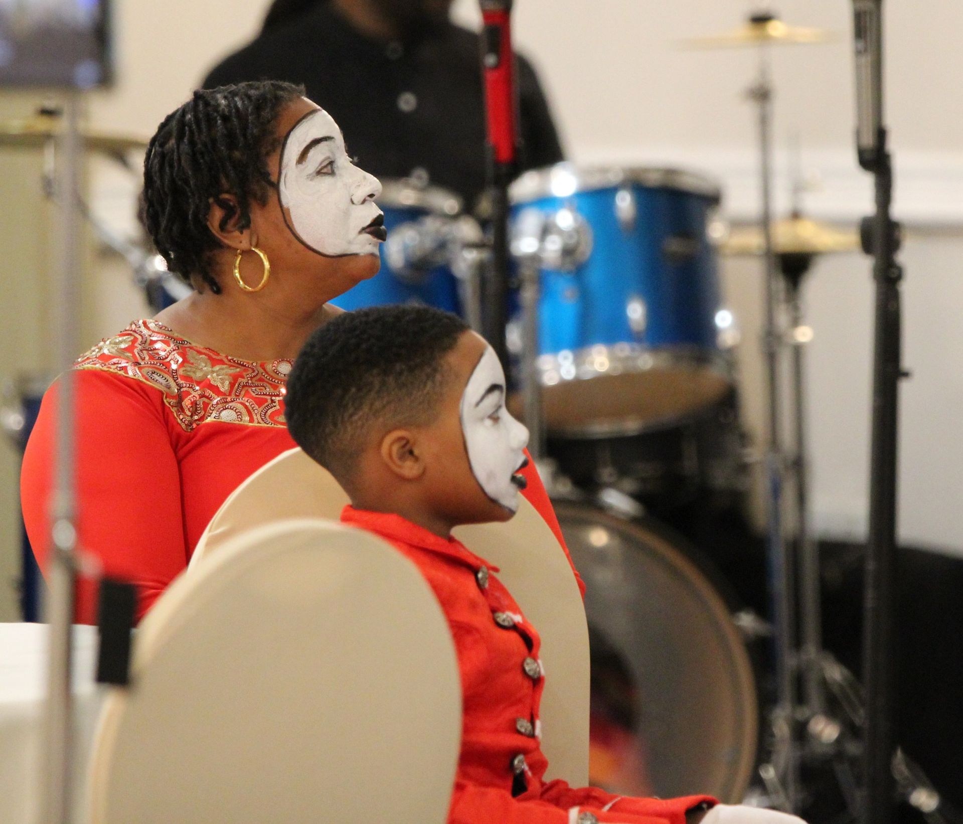 A woman and child are sitting in front of a drum set