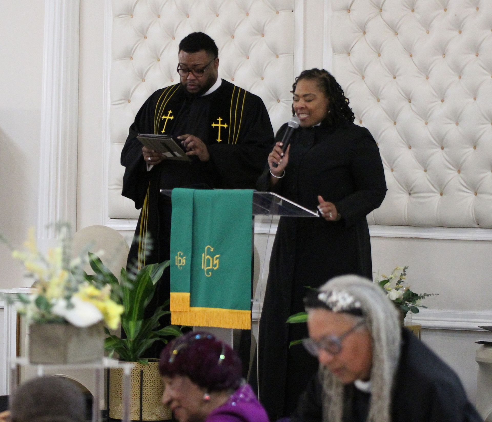 A man and a woman are standing at a podium in front of a group of people.