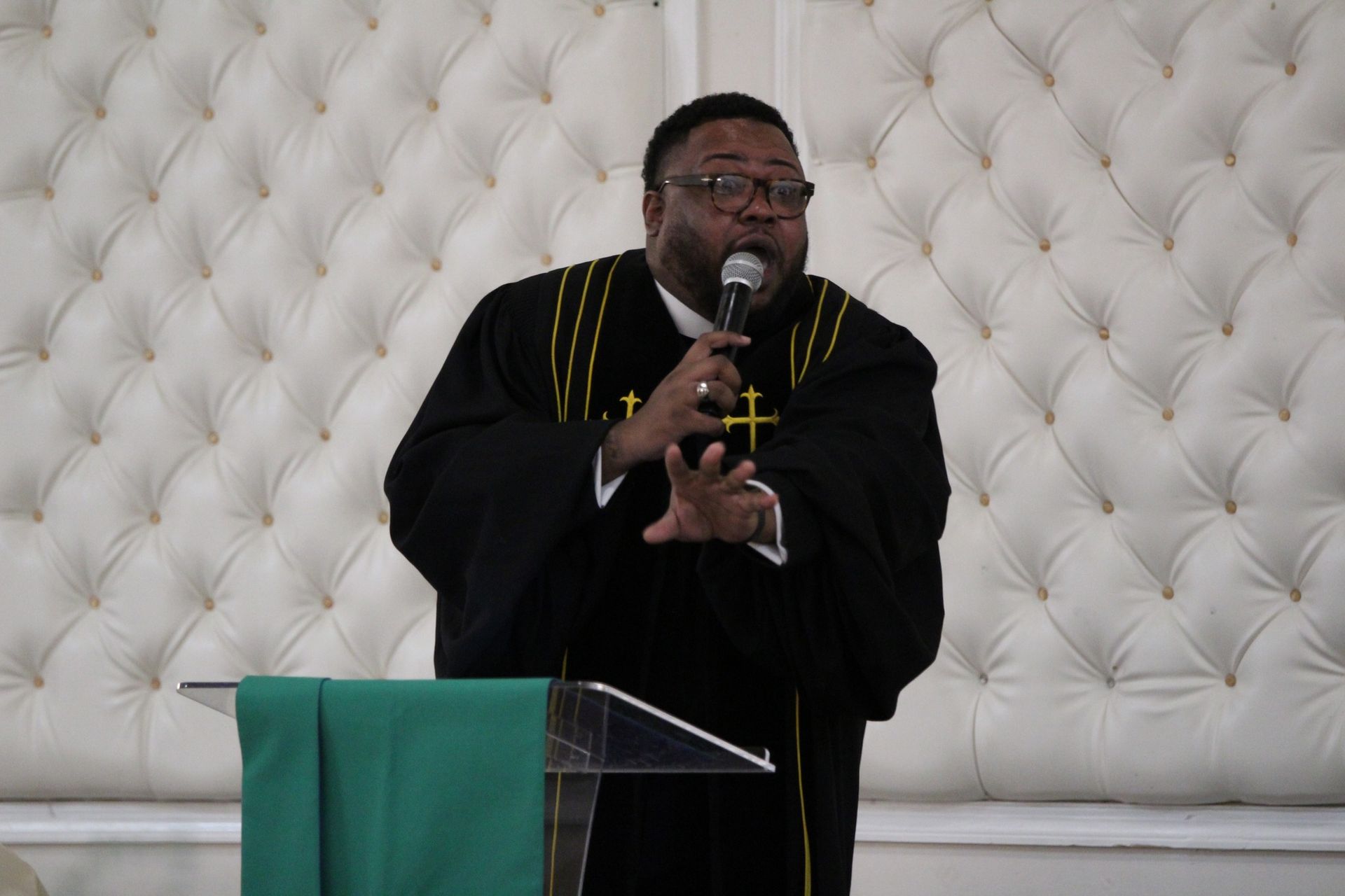 A man in a black robe is speaking into a microphone