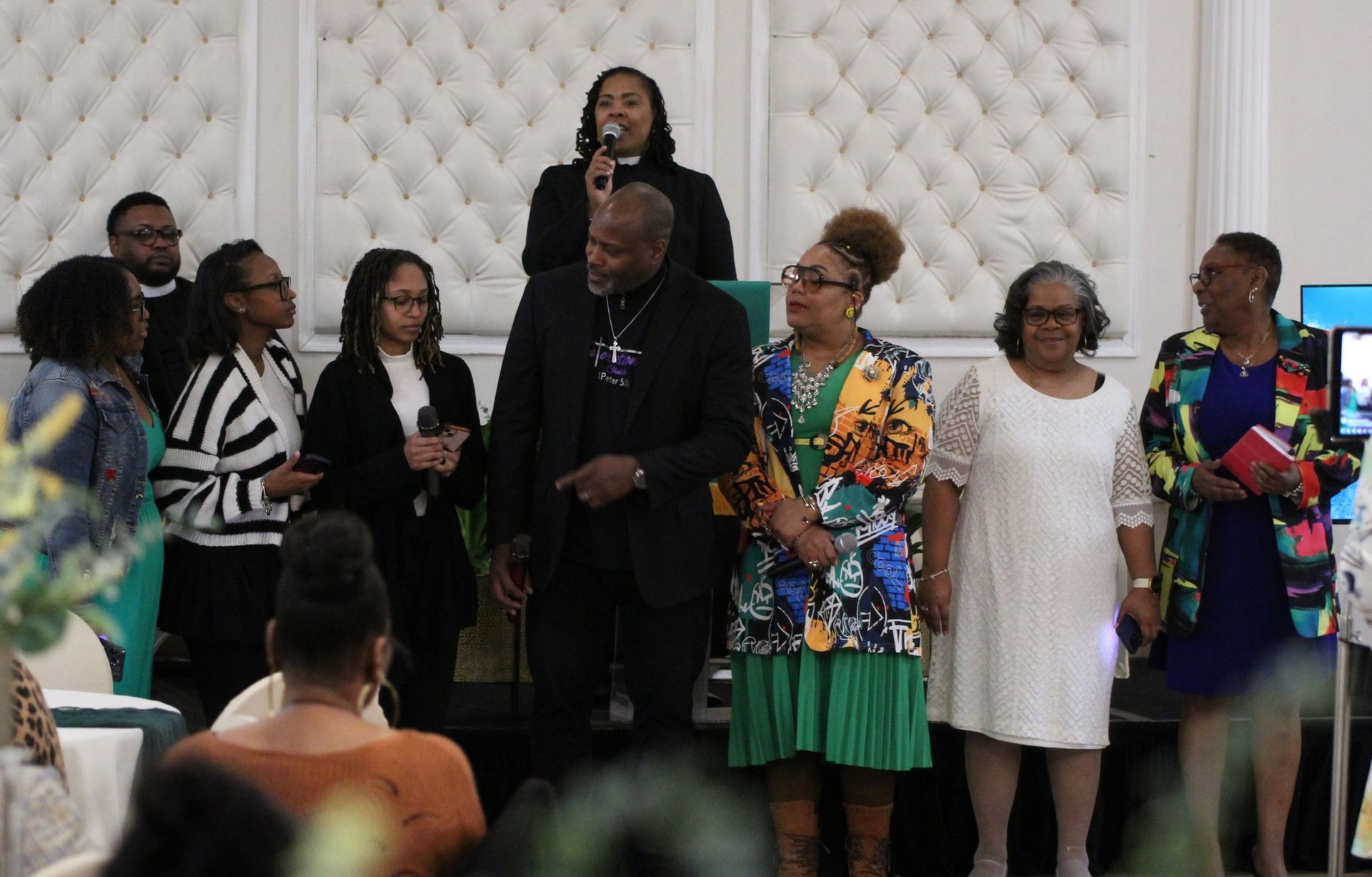 A group of people are standing in front of a microphone in a room.