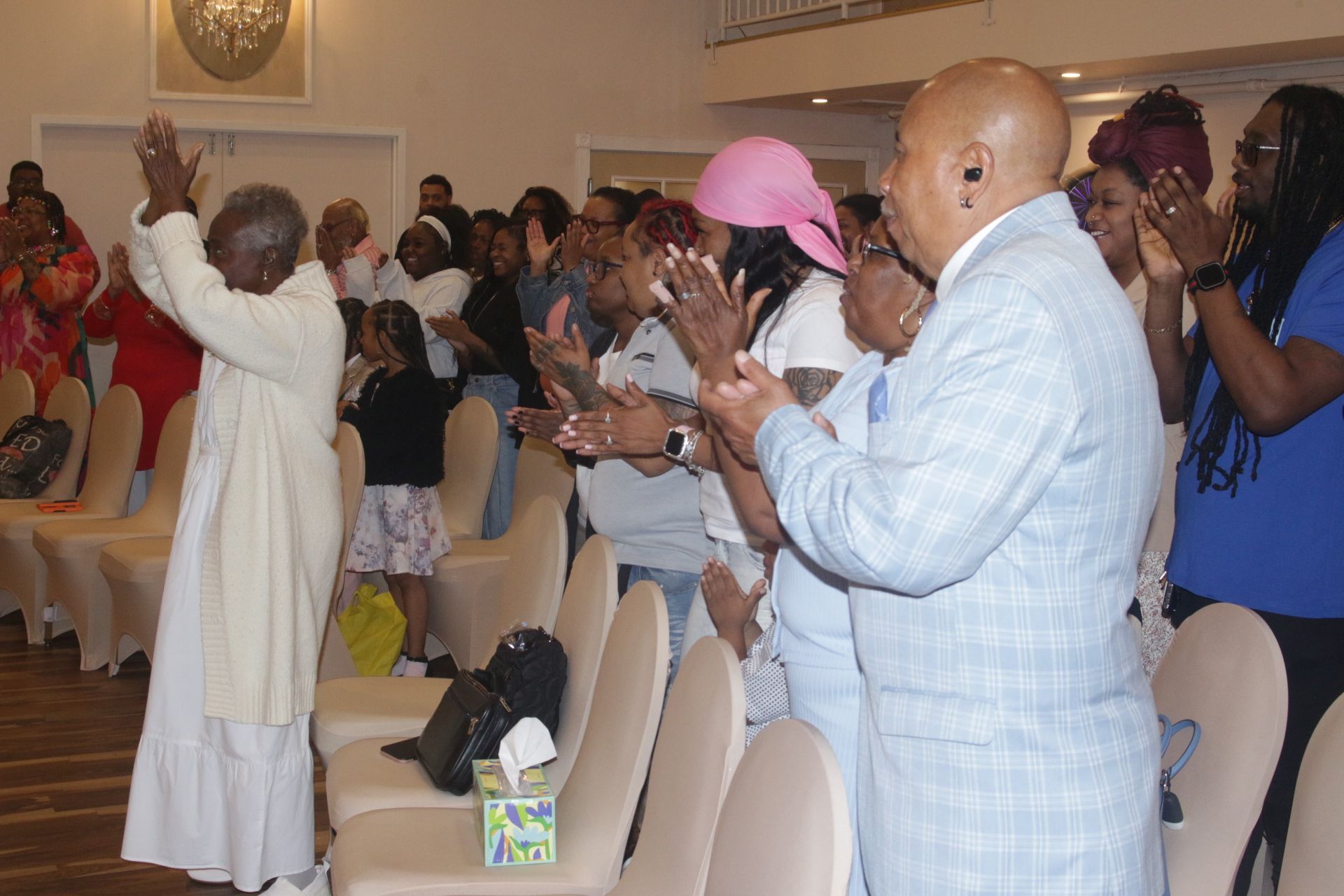 People standing and clapping during a church service in a bright hall