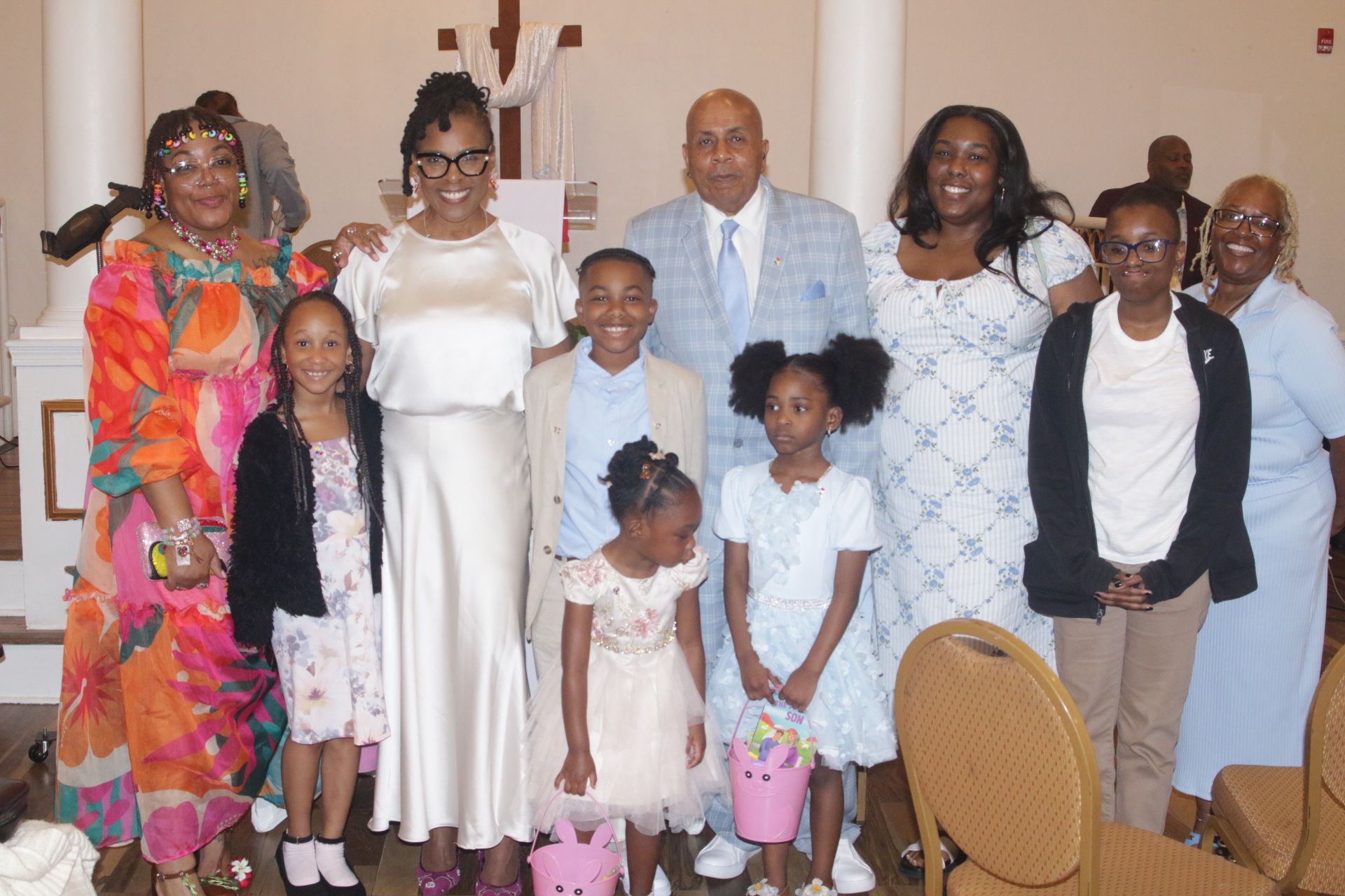 Group posing indoors at a celebration, smiling and dressed in formal attire.
