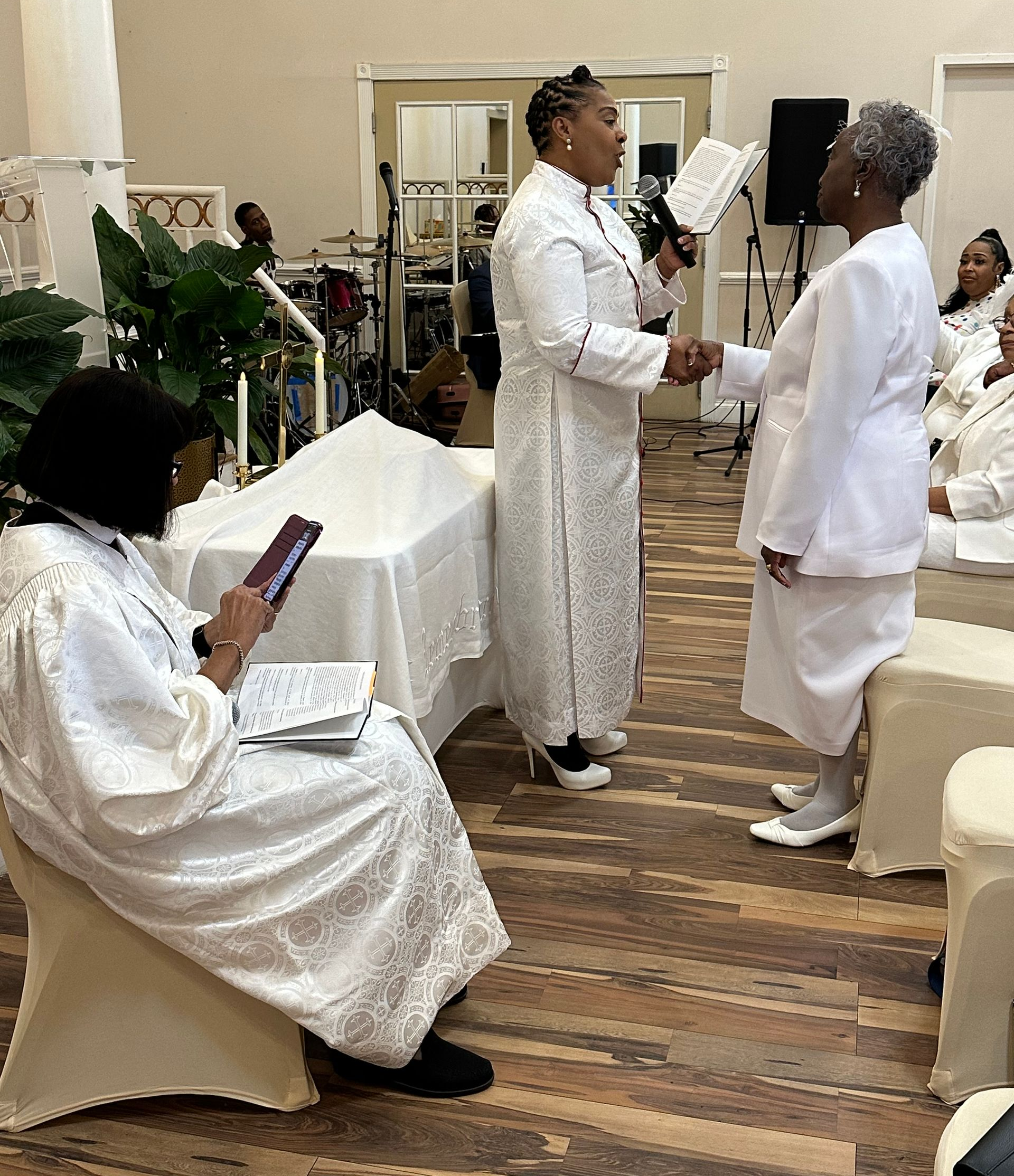 A group of women in white robes are standing in a room.