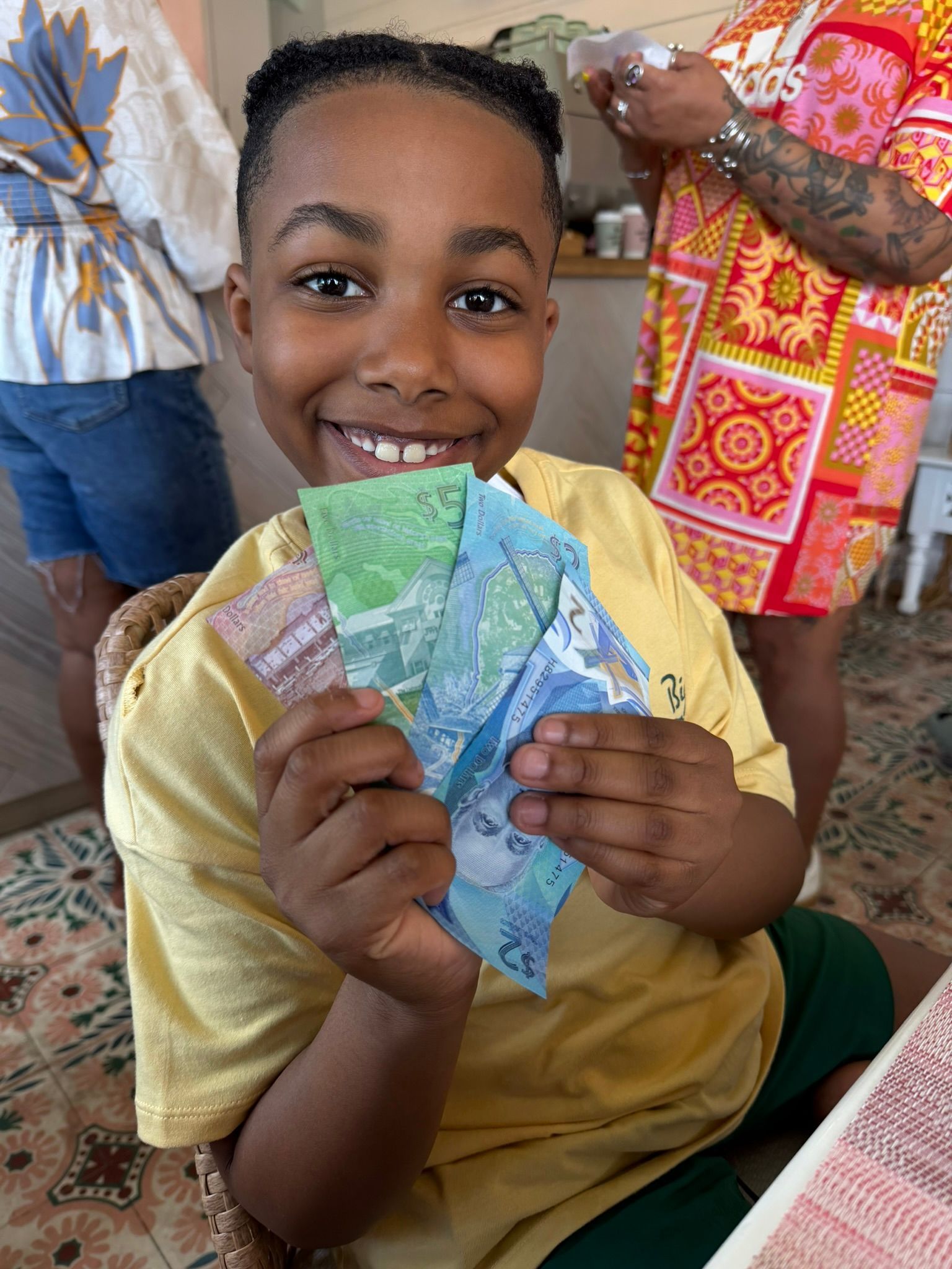 Smiling child holding colorful paper bills indoors