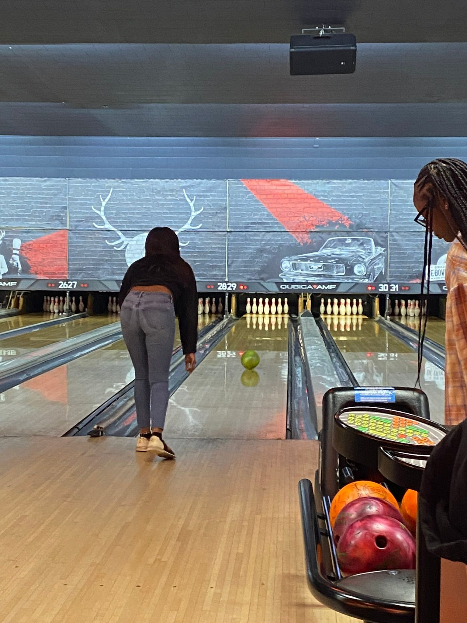 A woman is throwing a bowling ball on a bowling alley.