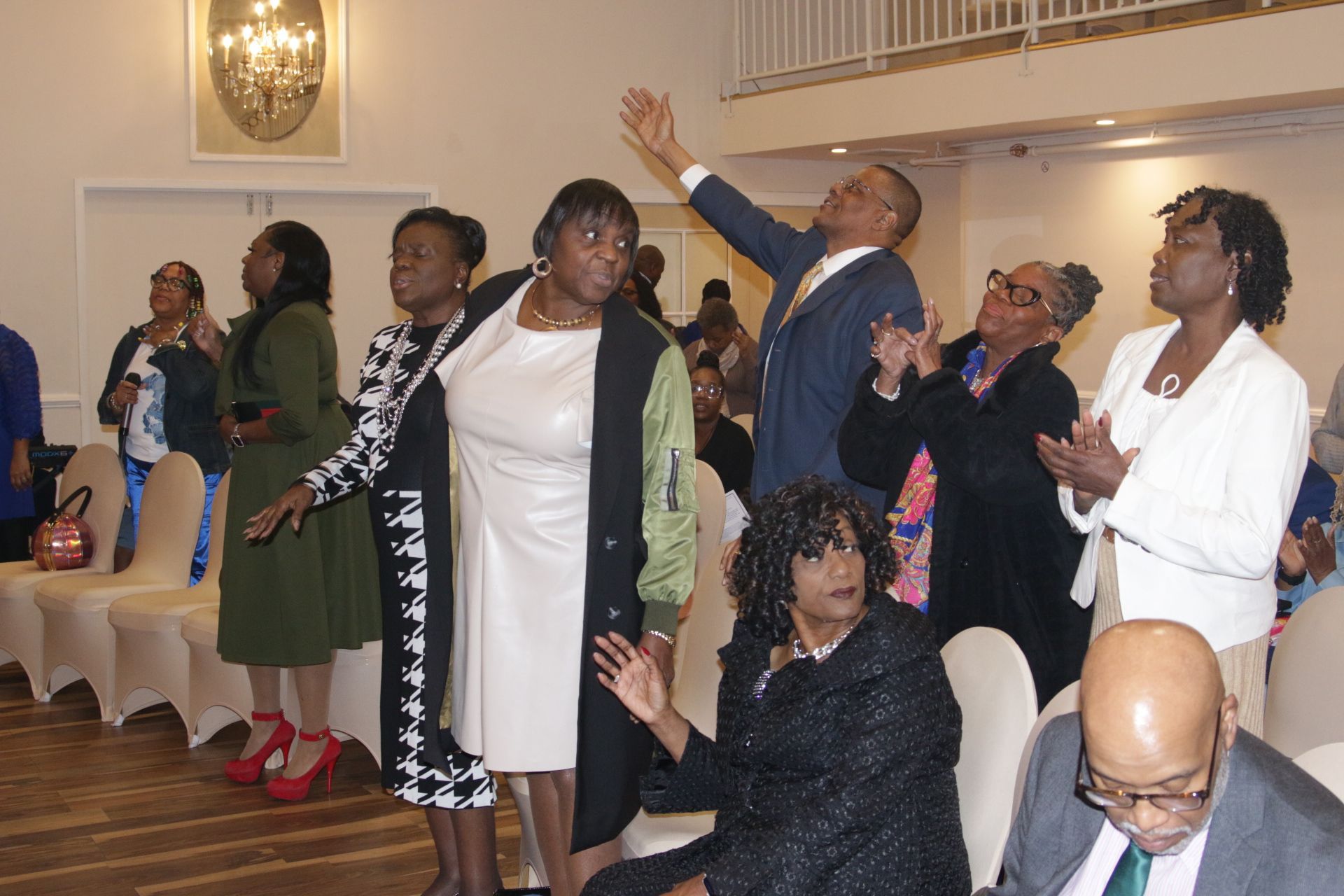 Group of people indoors singing and raising their hands during a lively celebration